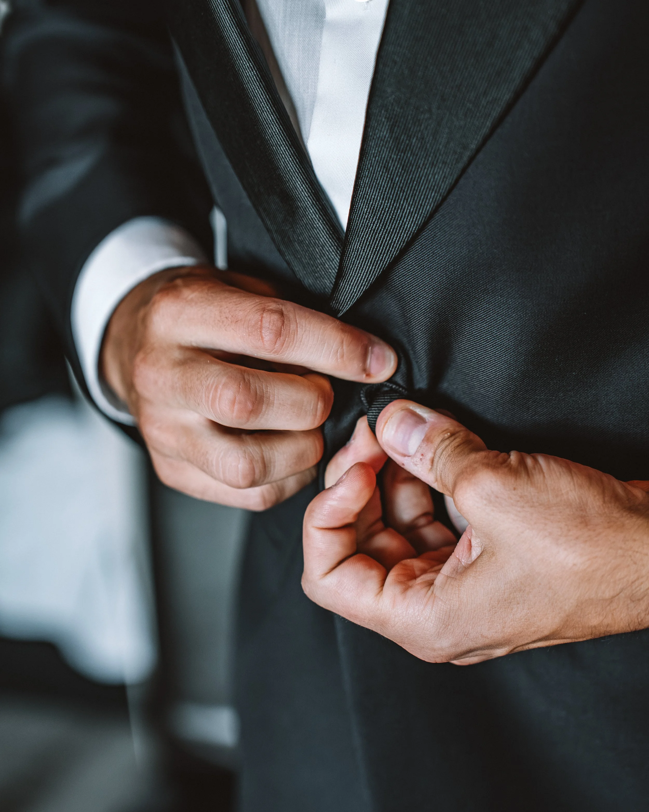 Person som knäpper knapp på svart kostym.