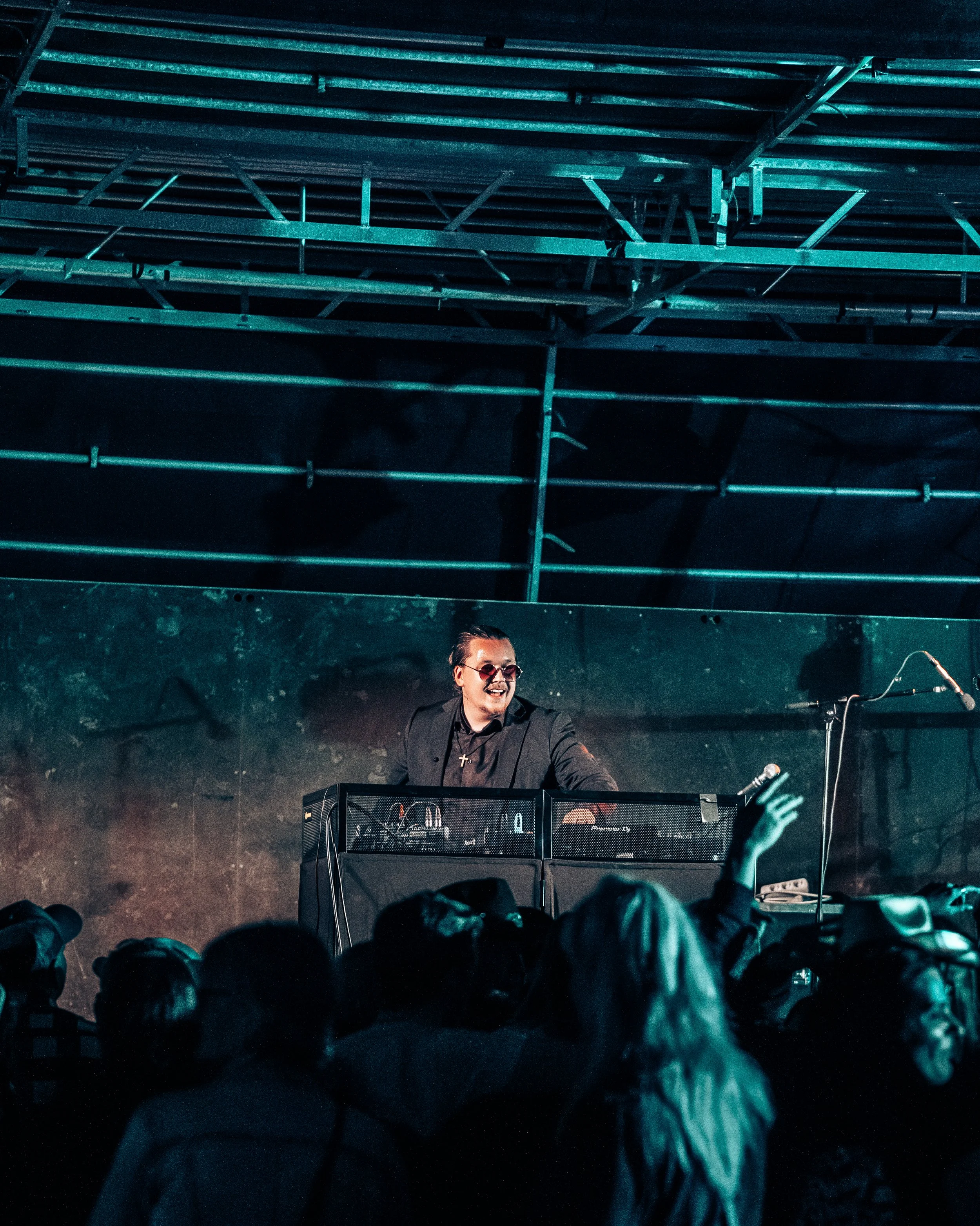 Joe Hanzen står som DJ på en scen, bär mörka kläder och solglasögon, och spelar inför en publik i Norrland som dansar.