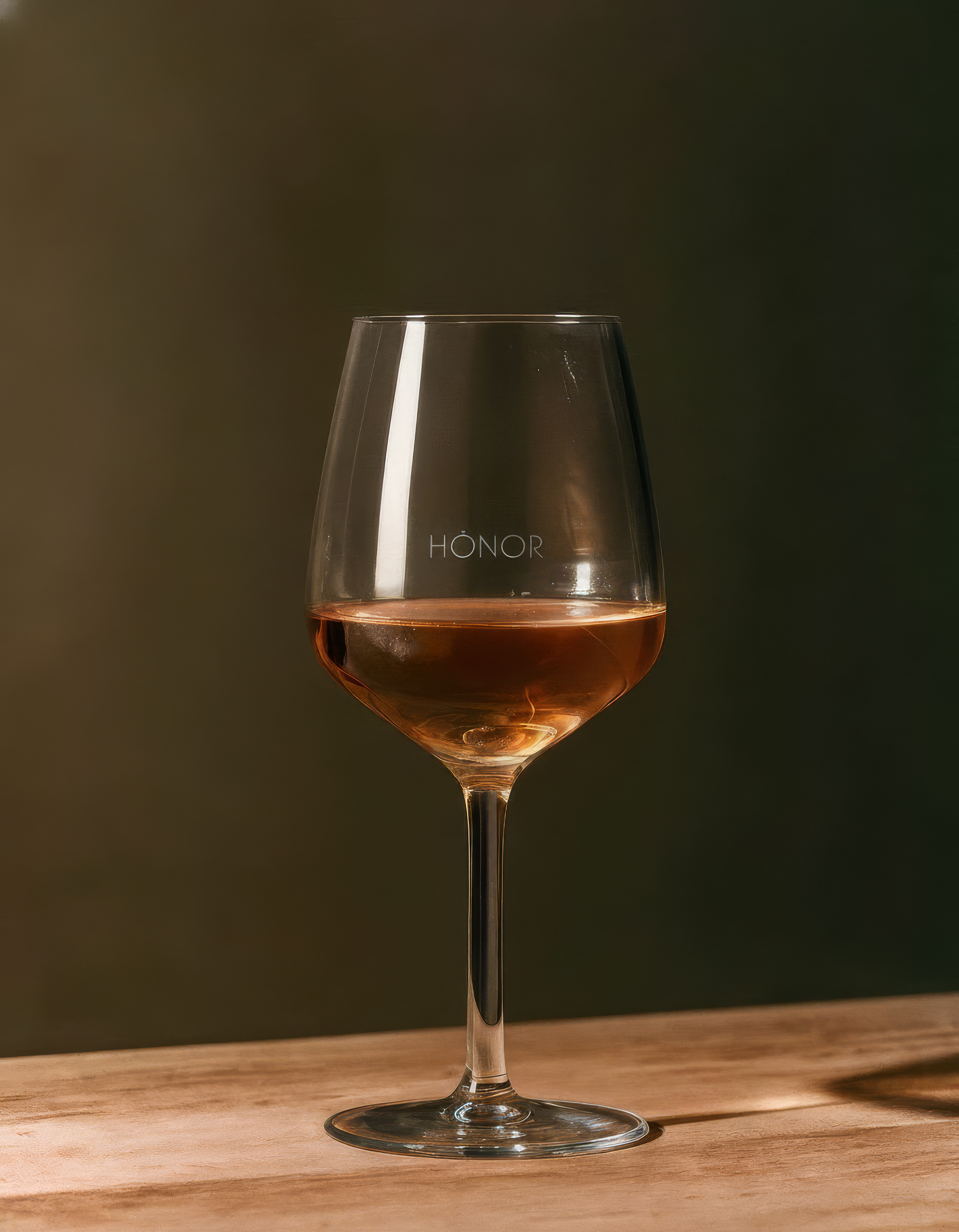 A wine glass filled with rosé wine on a wooden surface with a blurred background.