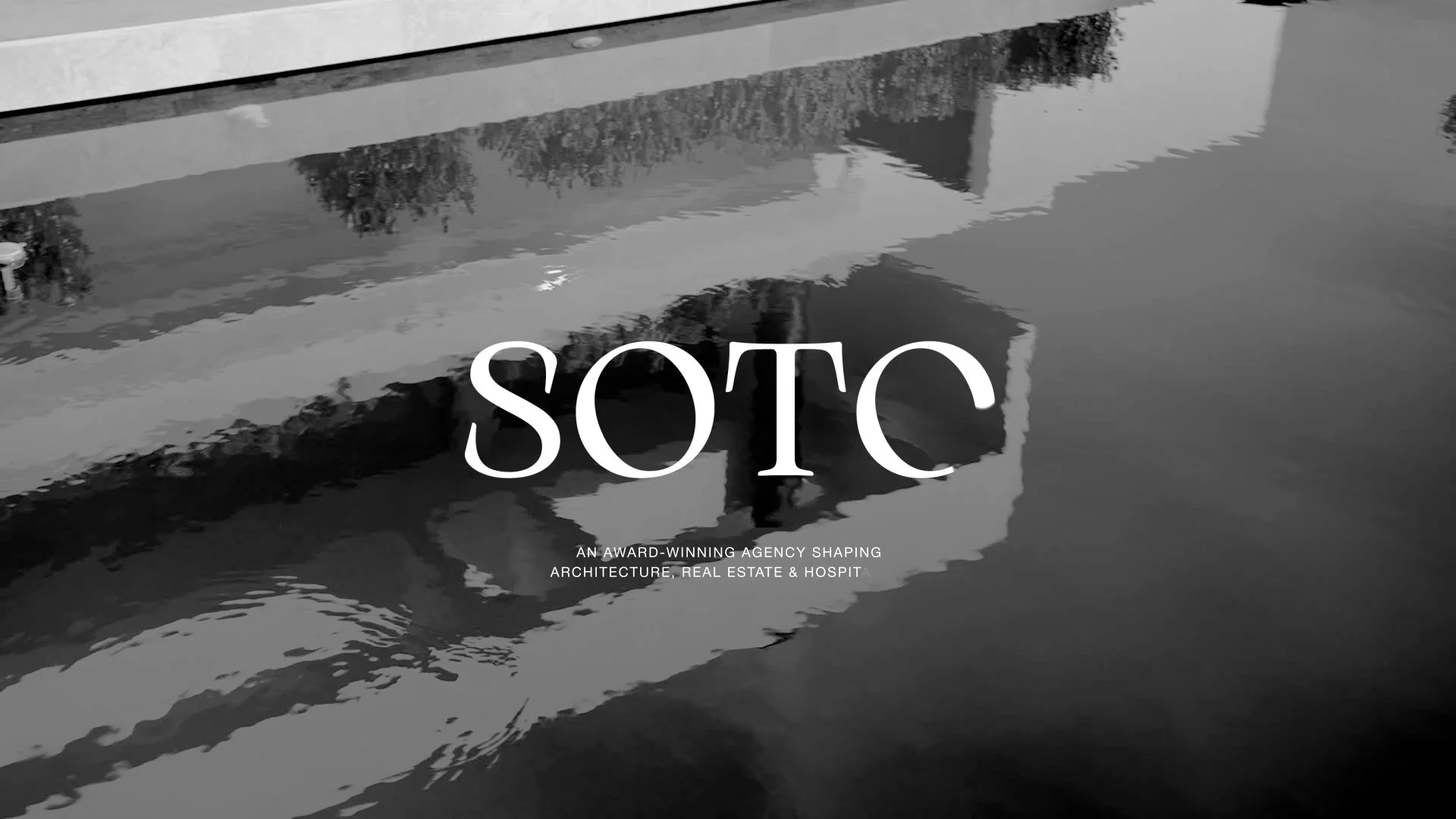 Black and white photo of a boat reflected in water with the word 'SOTC' in large white letters and smaller text reading 'An award-winning agency shaping architecture, real estate and hospital'.