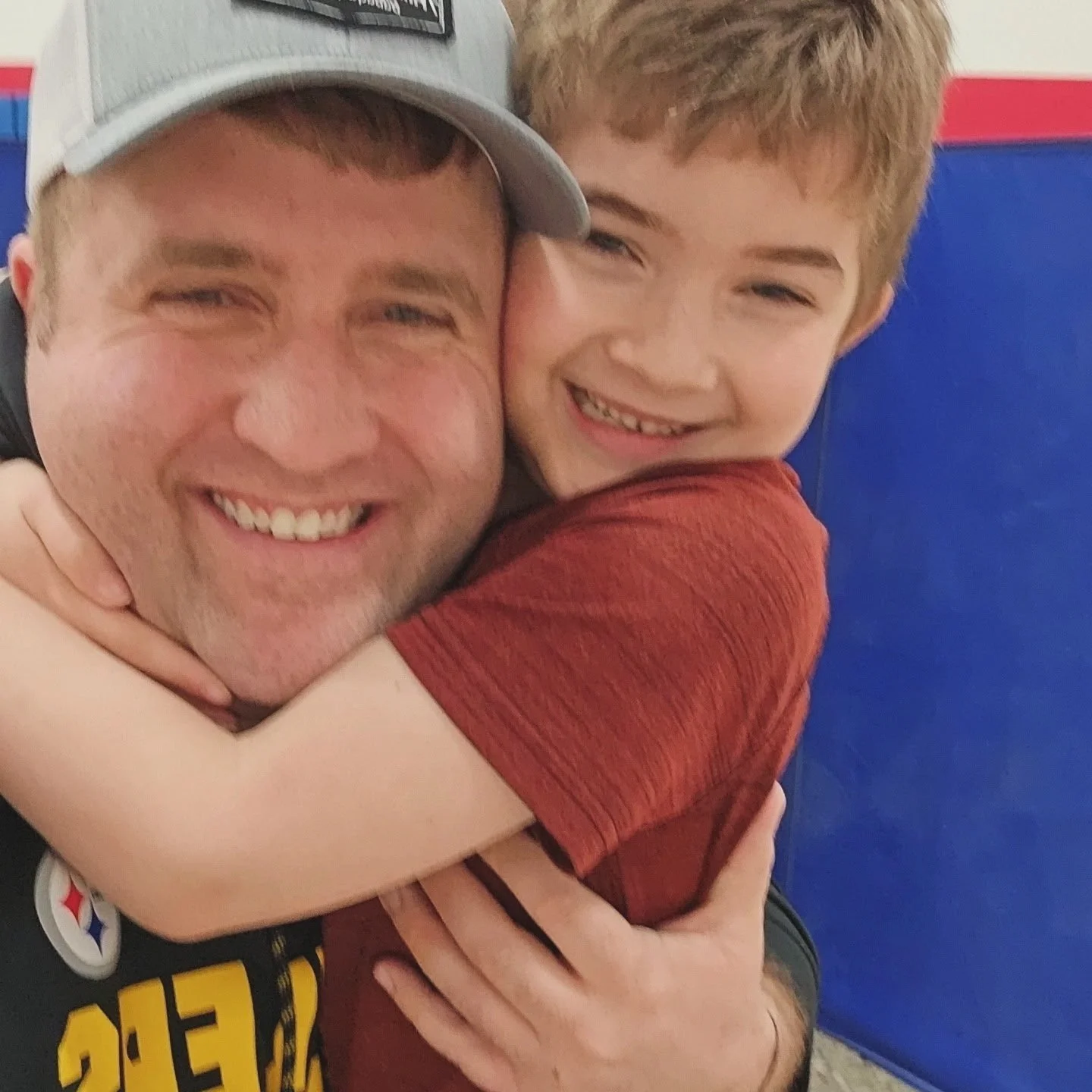 Mark and his son hugging and smiling, both showing happiness.