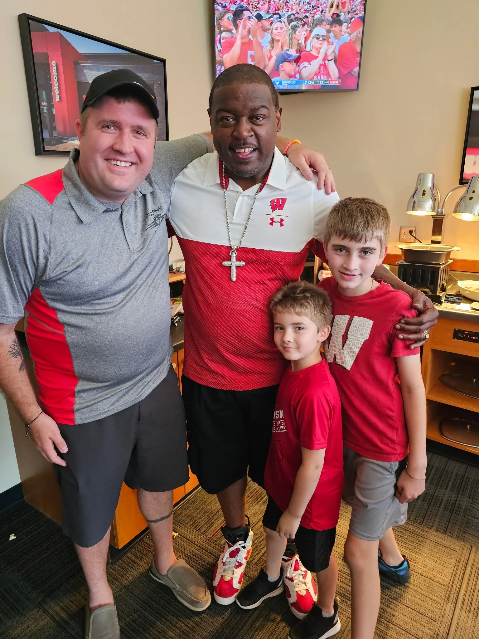 Mark, his sons, and Wisconsin football legend Ron Dayne, taking a photo together.