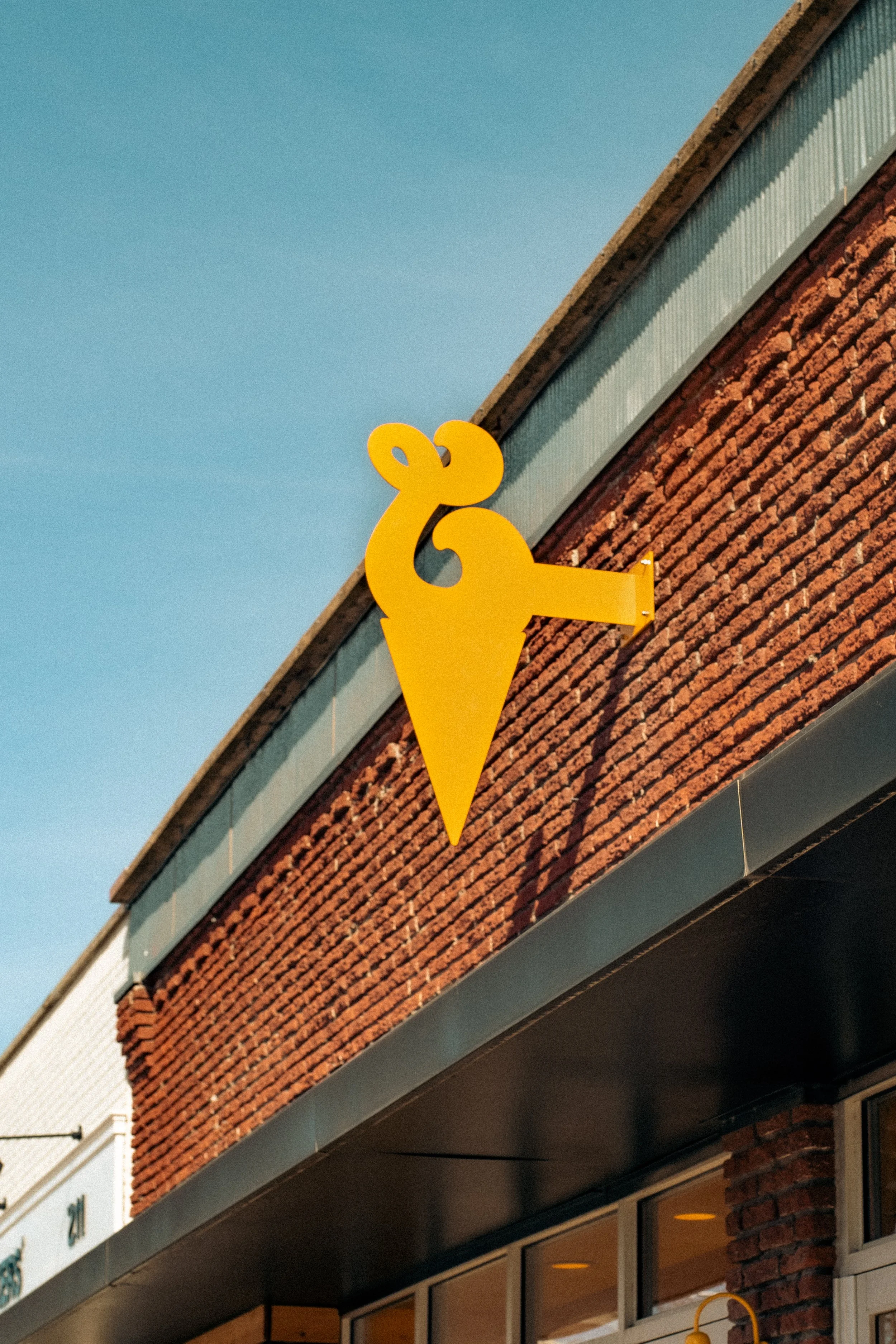 Yellow decorative lamb-shaped sign mounted on a brick building facade.