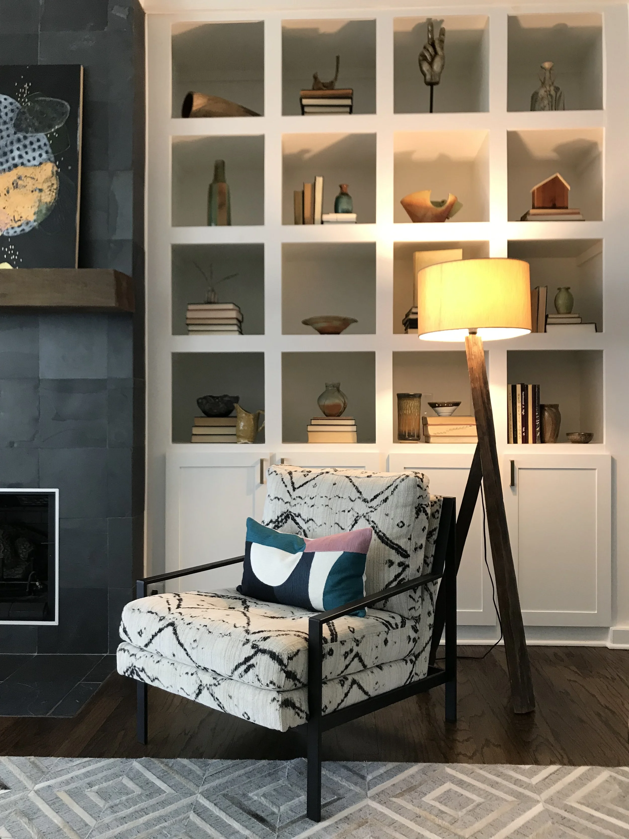 Hide rug, contemporary metal chair, sculptural floor lamp, ceramic collection built in display in living room designed by Dylan Turk. This southern home unites contemporary and traditional.