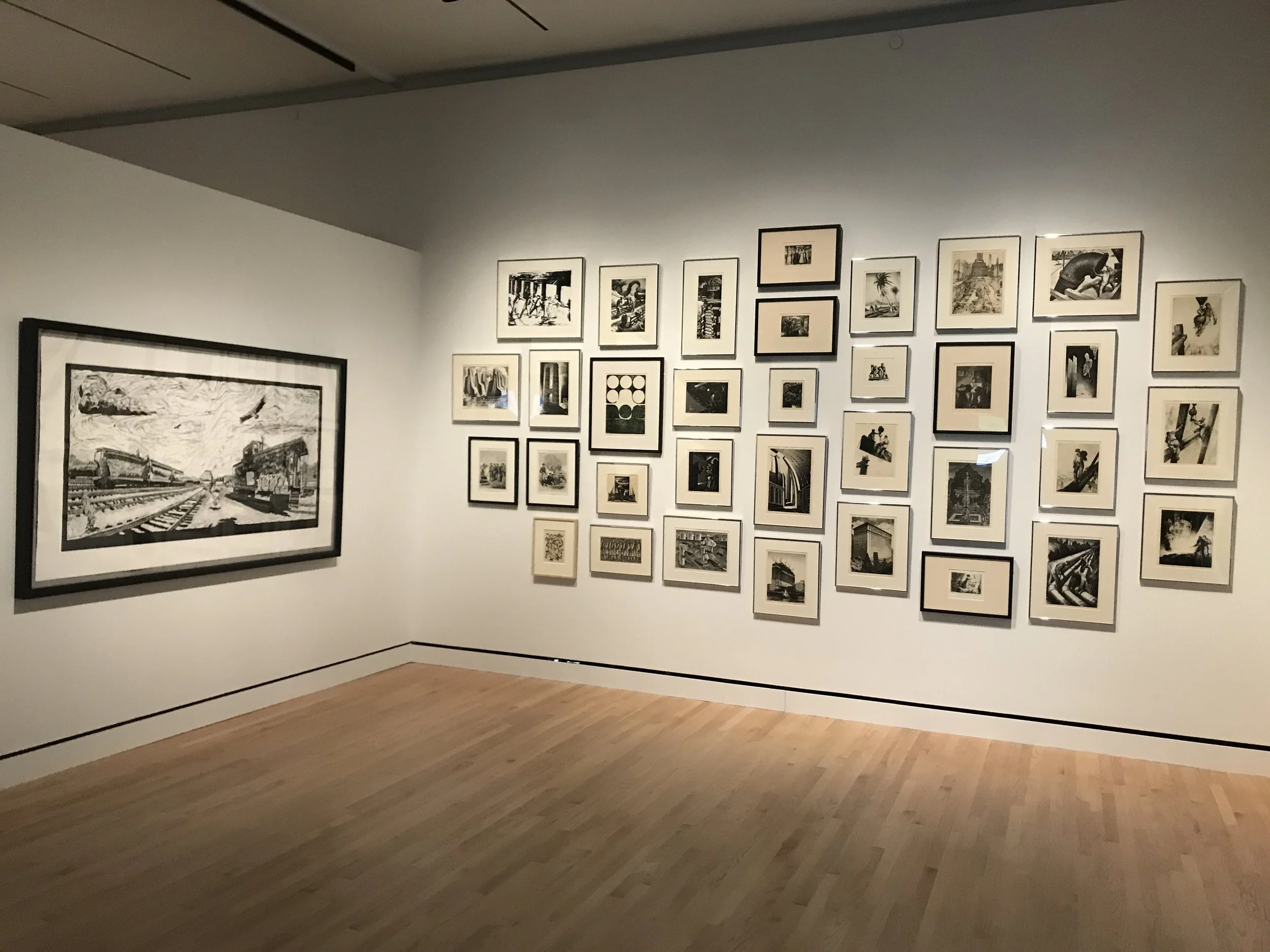 An art gallery with numerous framed black and white photographs displayed on a white wall.