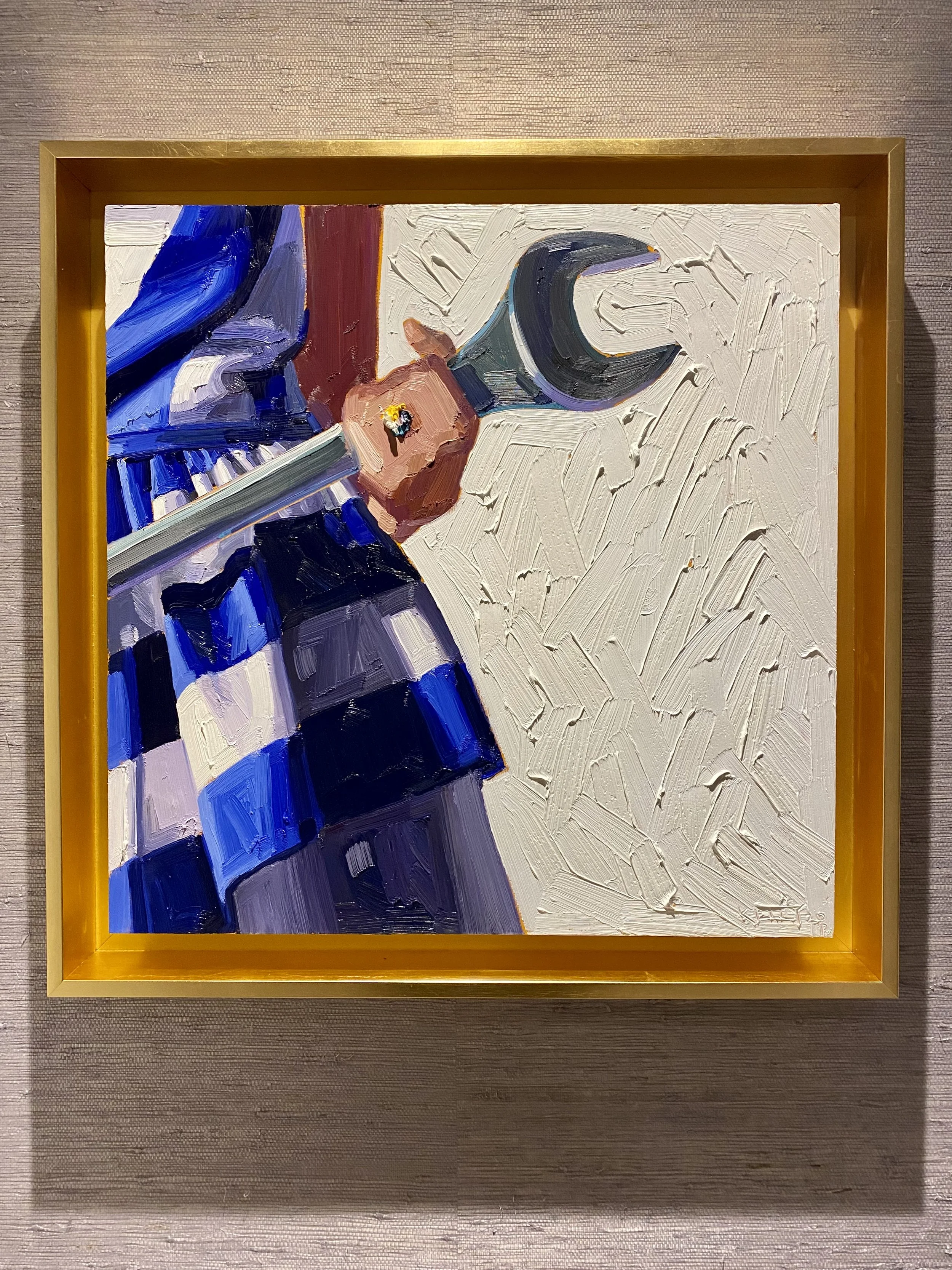 An abstract painting featuring a stylized figure of a woman in a blue dress, with a prominent hand in the foreground, painted with bold brushstrokes on a textured white background, framed in gold.