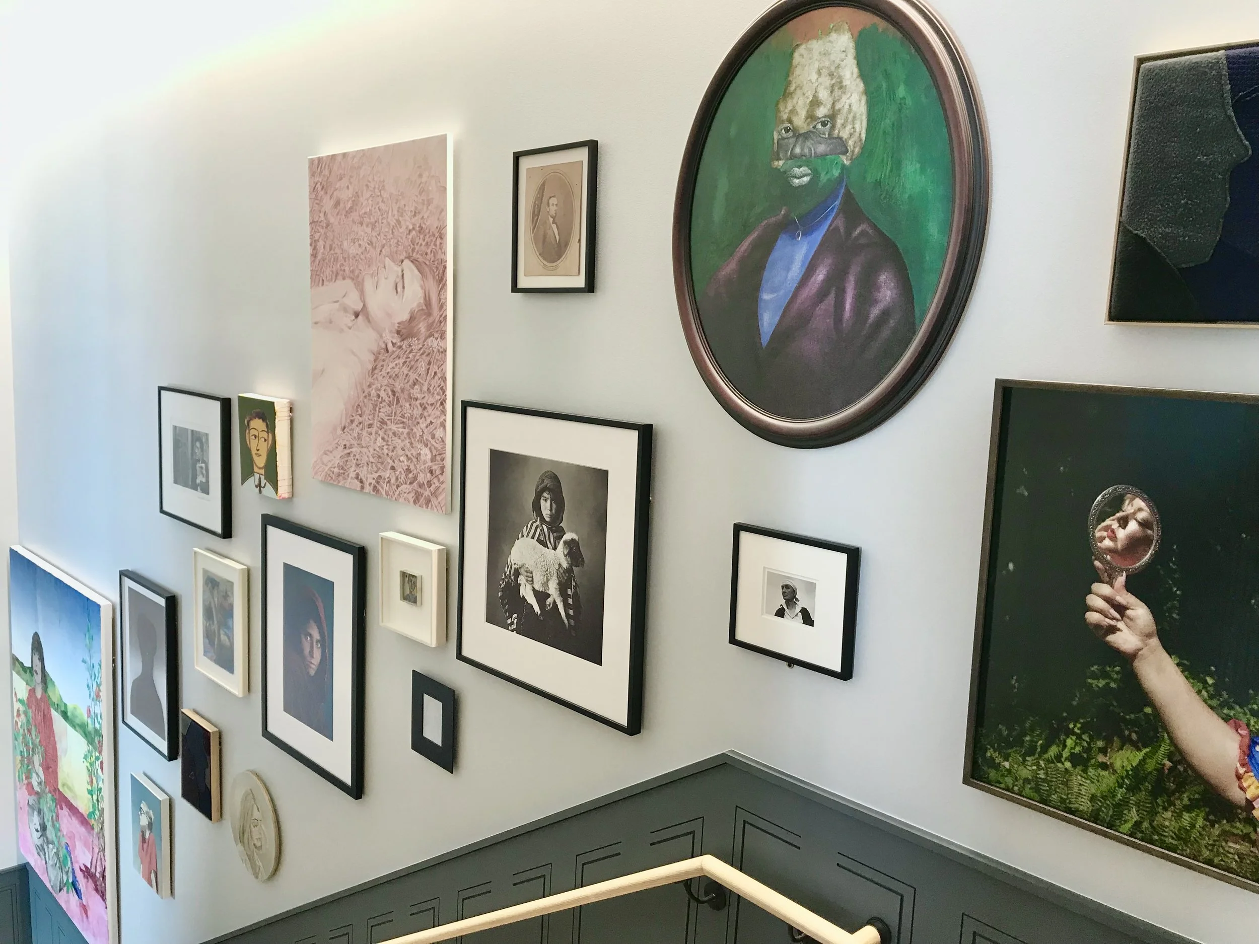 contemporary art in a salon hang down a stairwell. Member's club designed and curated by Dylan Turk.