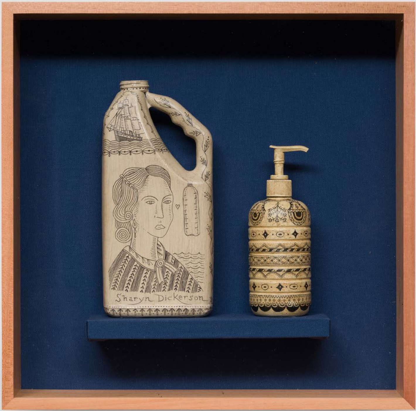 Two decorative bottles, one taller with drawn artwork and name. The shorter one has intricate patterned designs in black and beige, with a pump dispenser. Both bottles are displayed in a wooden frame with a blue background.