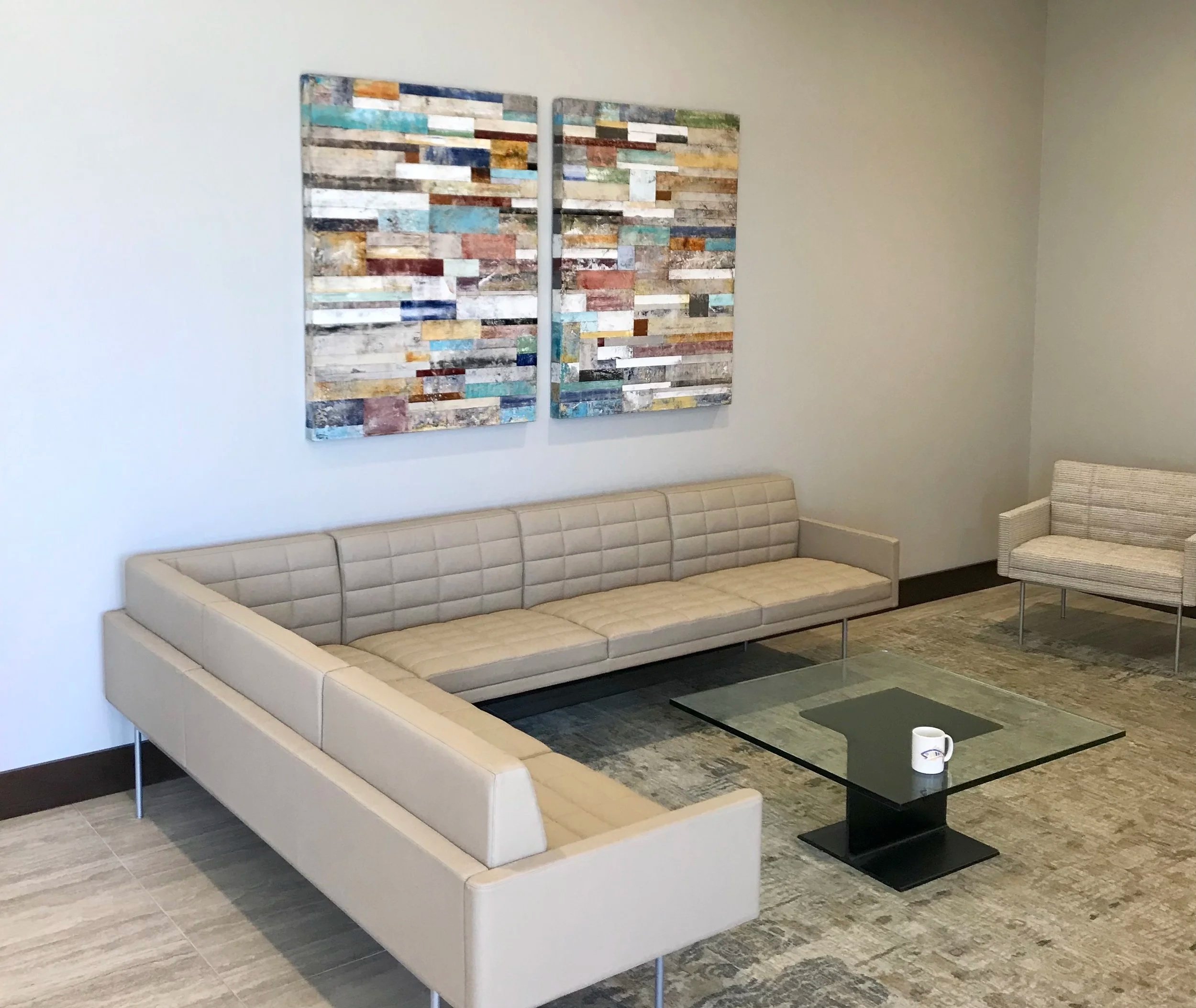 Living room with beige sectional sofa, black coffee table, and colorful abstract wall art.