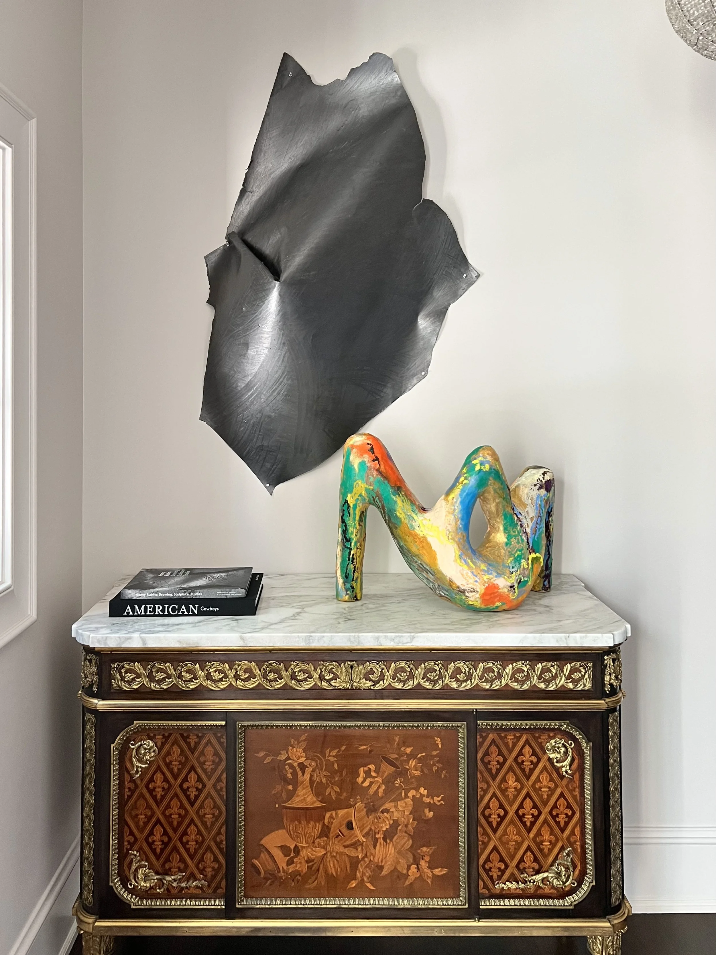 A gilded French antique marble topped cabinet and a contemporary wall drawing by Nancy Rubins anchor this vestibule in the Austin Westlake village mansion.