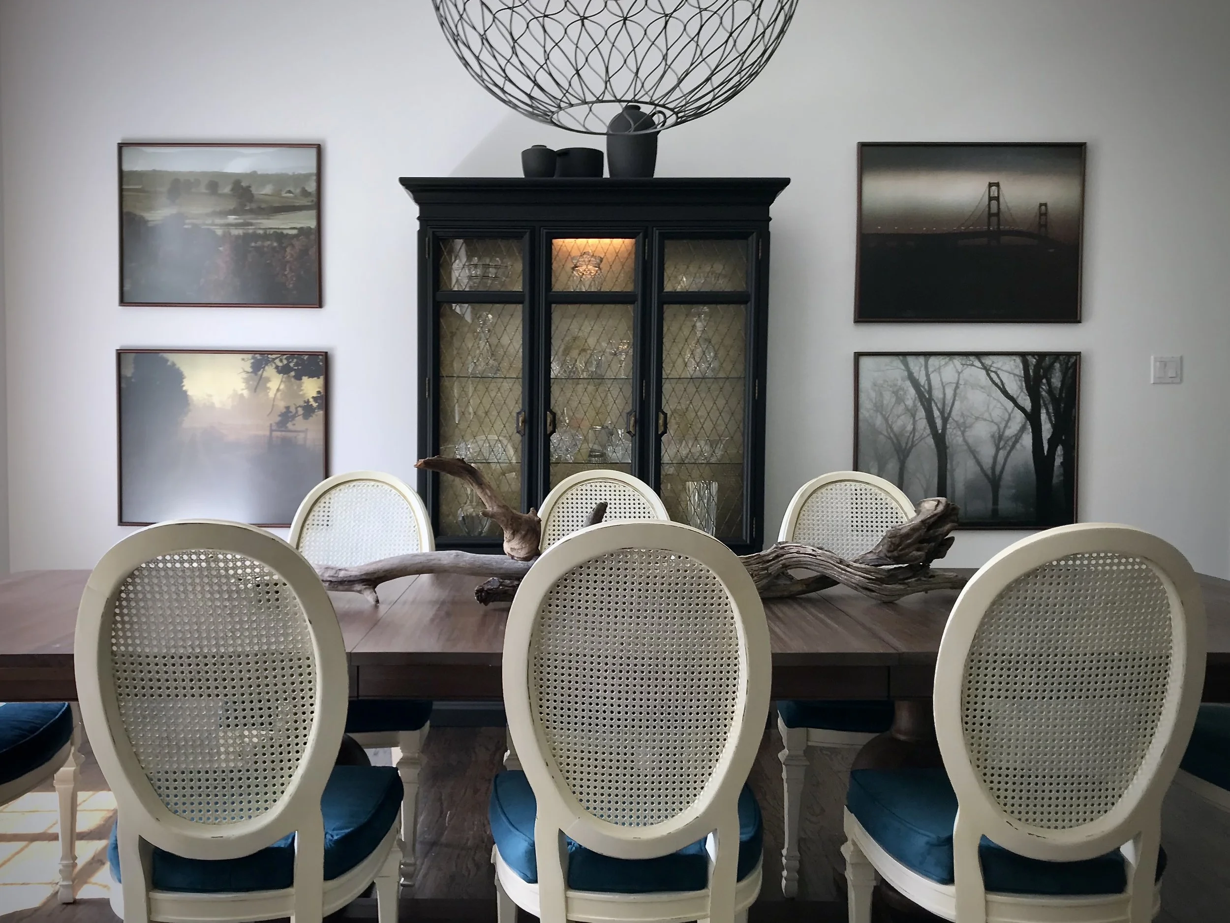 Contemporary Traditional dining room, black and gold china cabinet, large format photography, and sculptural driftwood. This southern home is designed by Dylan Turk.