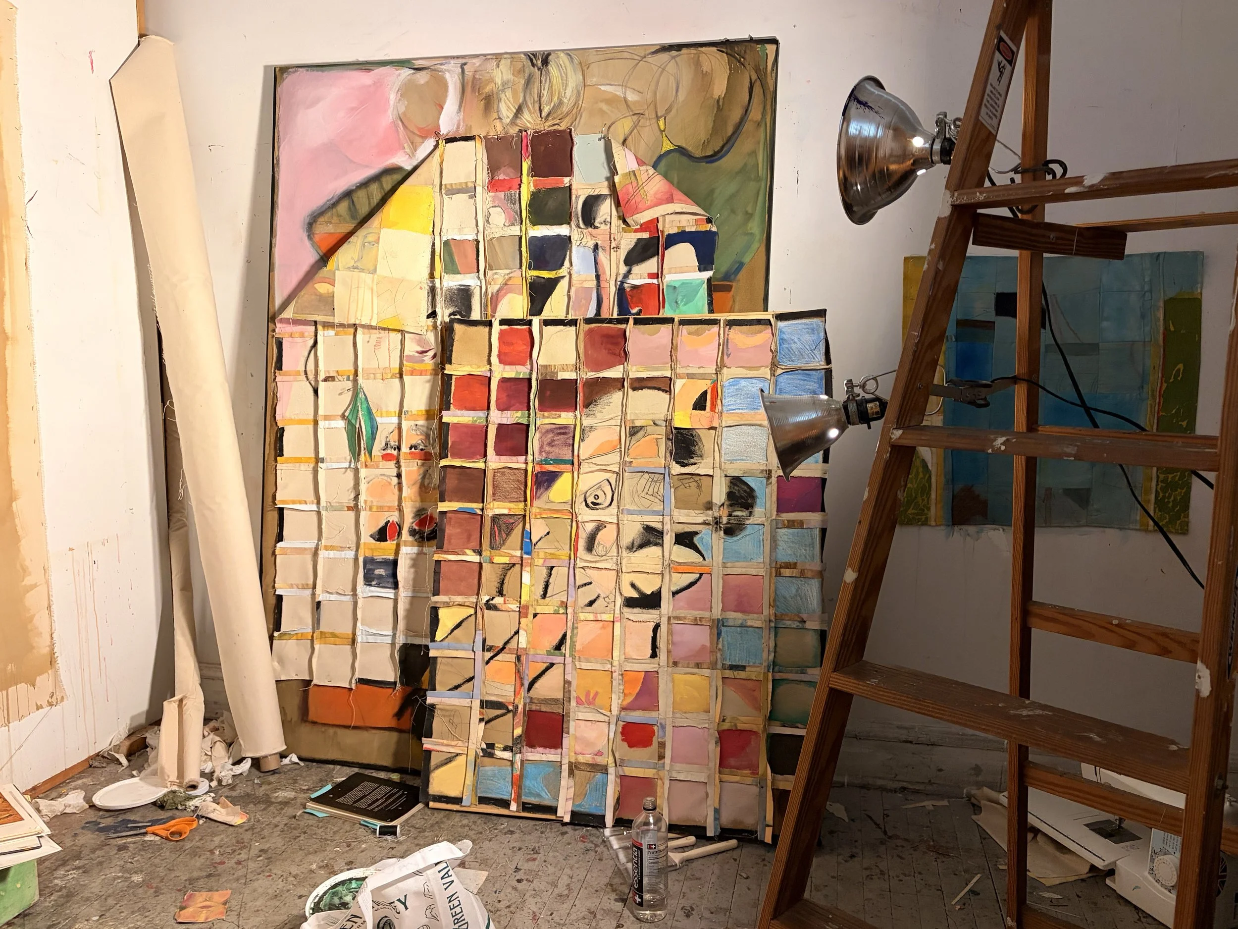 An art studio with a large abstract painting on the wall, a watercolor palette and brushes, and a ladder. Various art supplies and debris are scattered on the floor.