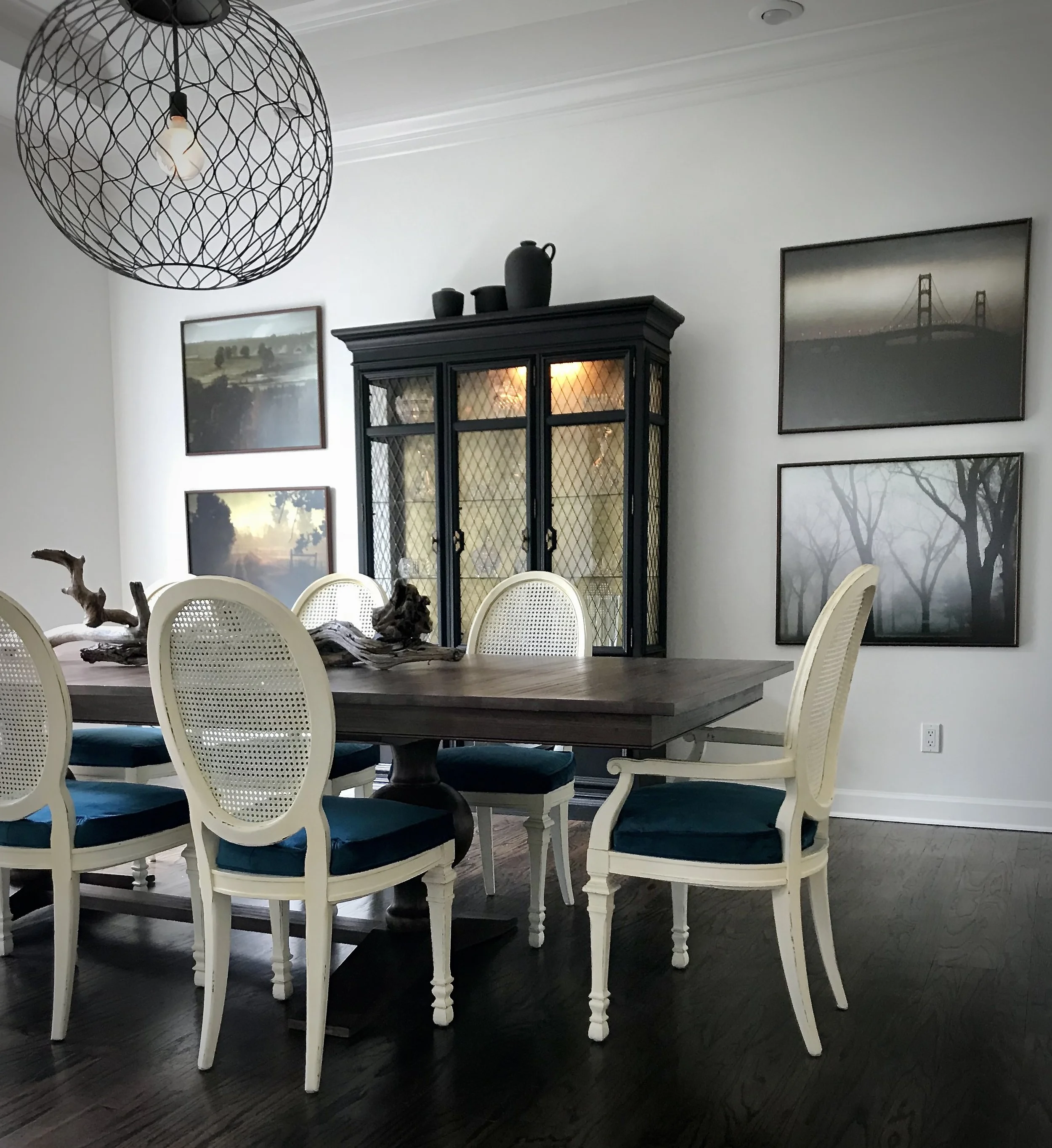 Dark wood floors, large sculptural wooden French dining table, antique cane backed dining chairs, china cabinet, and large scale photography. This southern home, designed by Dylan Turk.