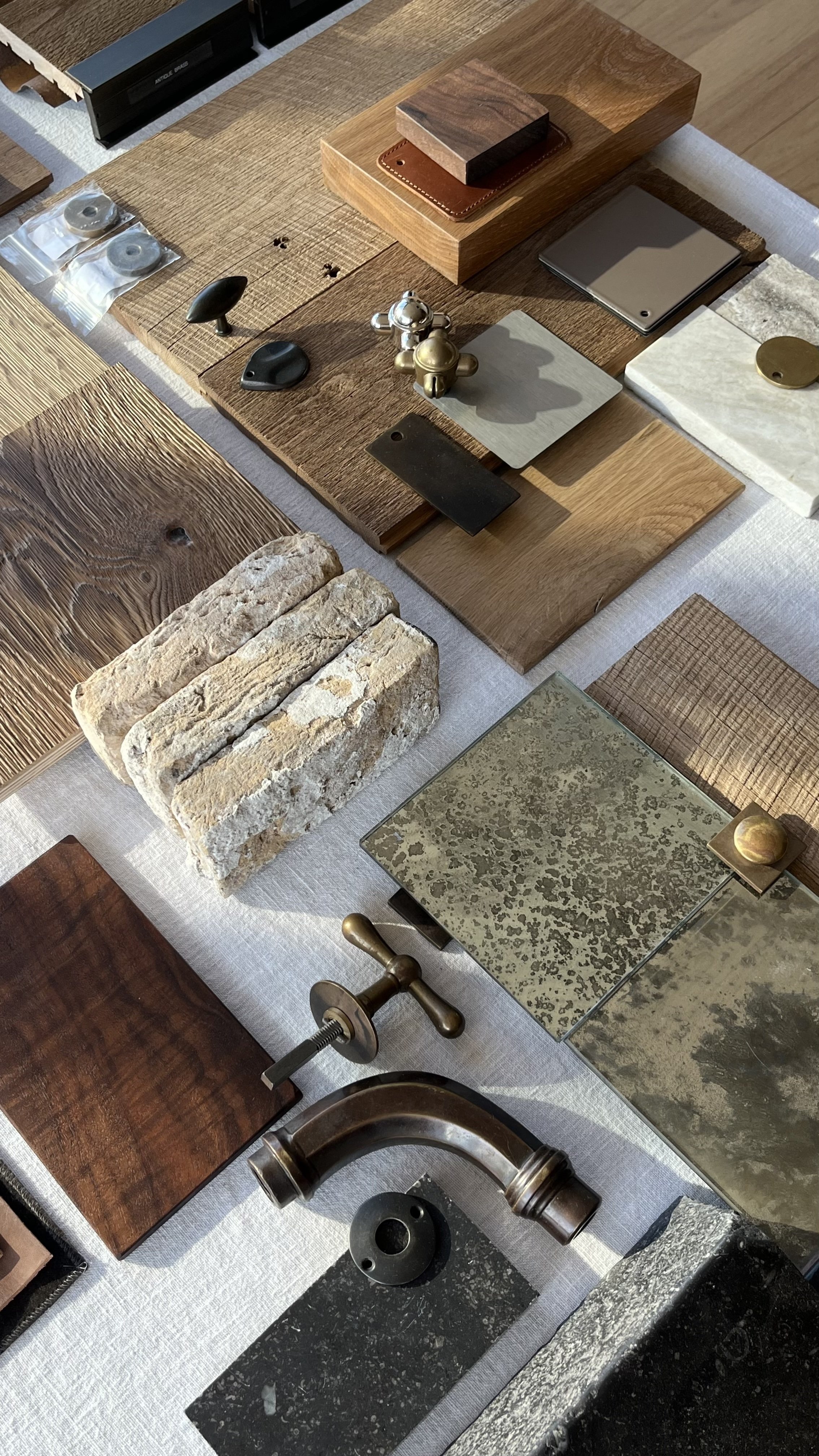 A display of various material samples including wood, stone, metal, and decorative pieces arranged on a white fabric tablecloth.