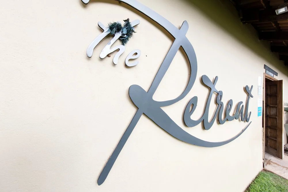 Sign on a wall reading 'the Retreat' with a decorative umbrella hook.