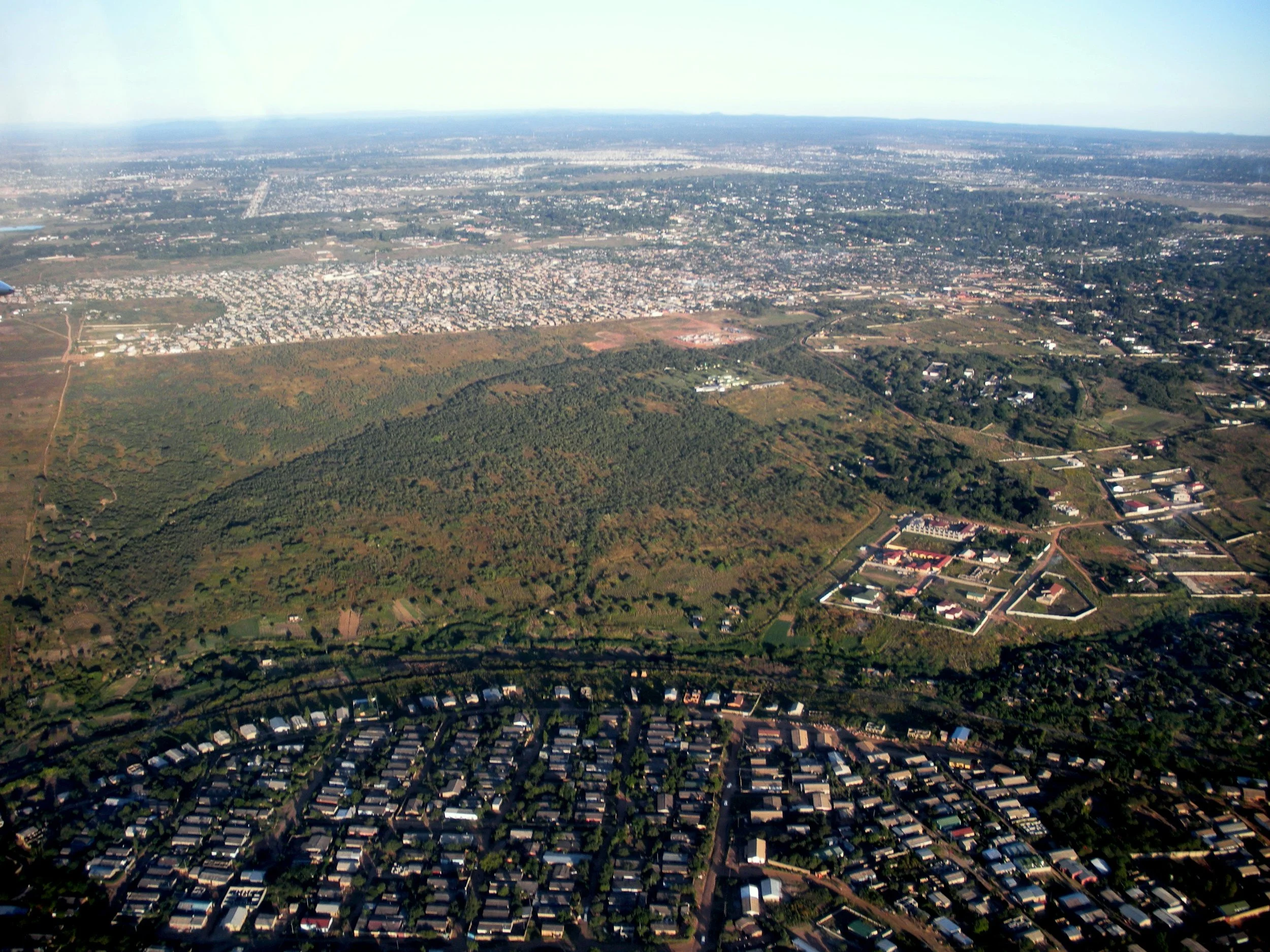 Aerial view of Roma Park pre construction in Lusaka with a large green park in the foreground and numerous residential and commercial areas extending into the distance.