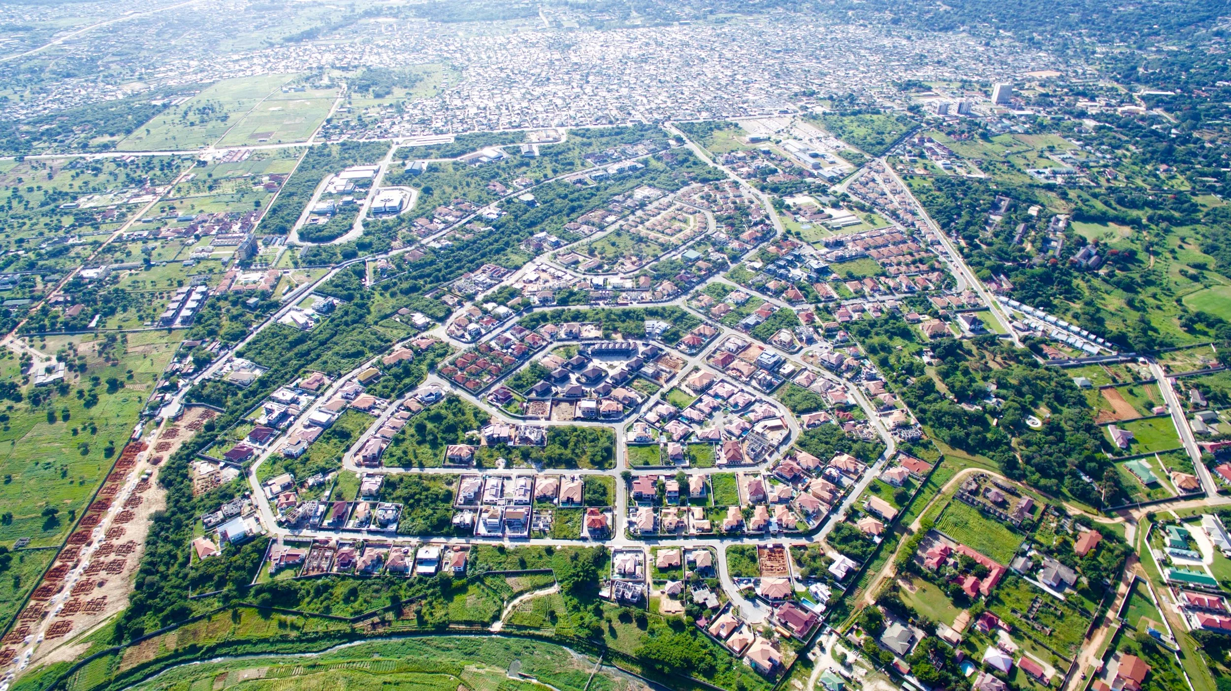 Aerial view of Roma Park with a mix of residential houses, green spaces, and some commercial buildings, with roads connecting the area.
