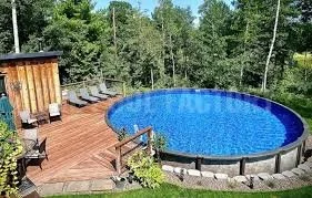 An outdoor wooden deck with a round swimming pool and surrounding trees.