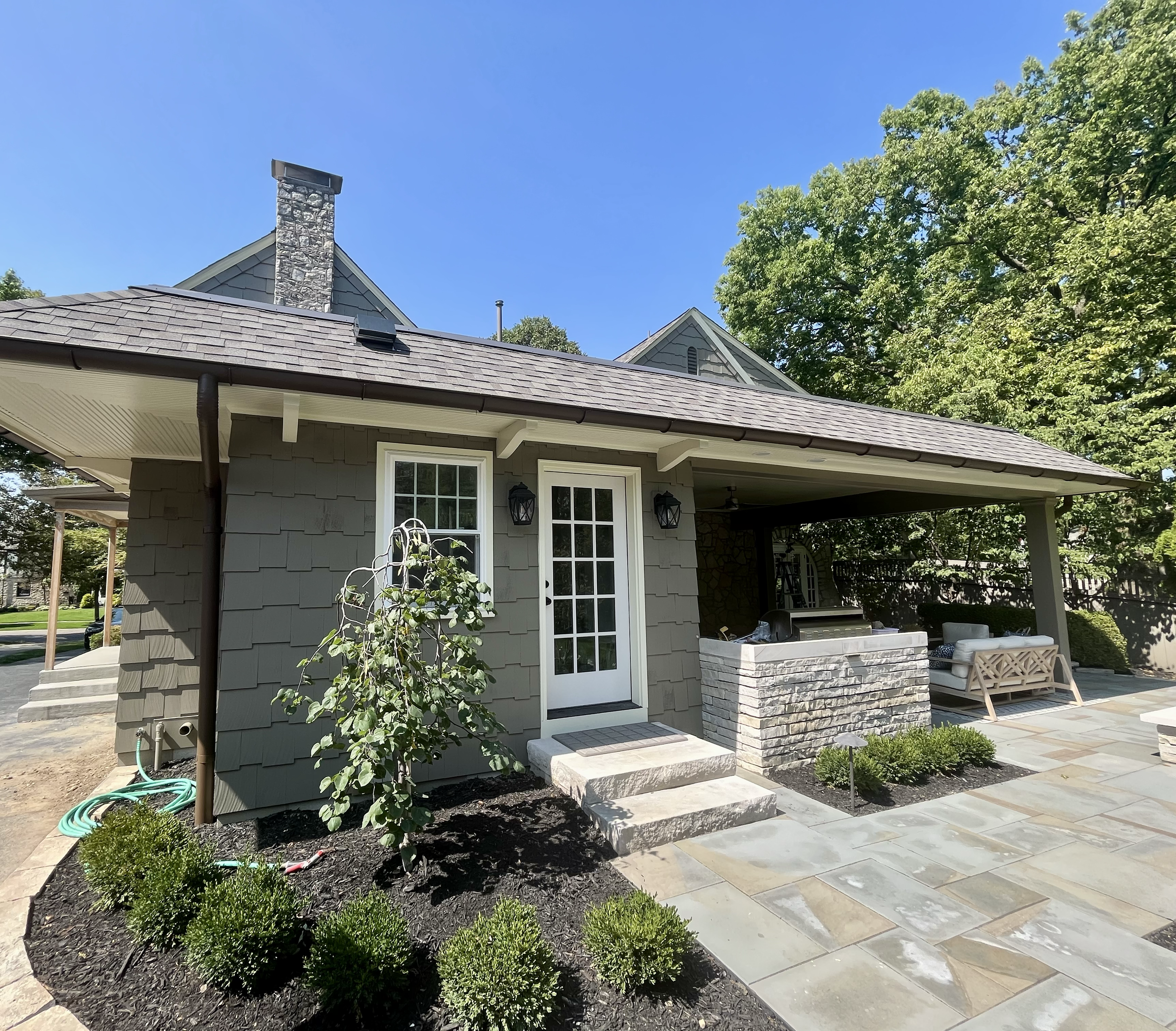 Exterior house painting project featuring gray siding, white trim, and covered patio on residential home in Upper Arlington, Ohio.