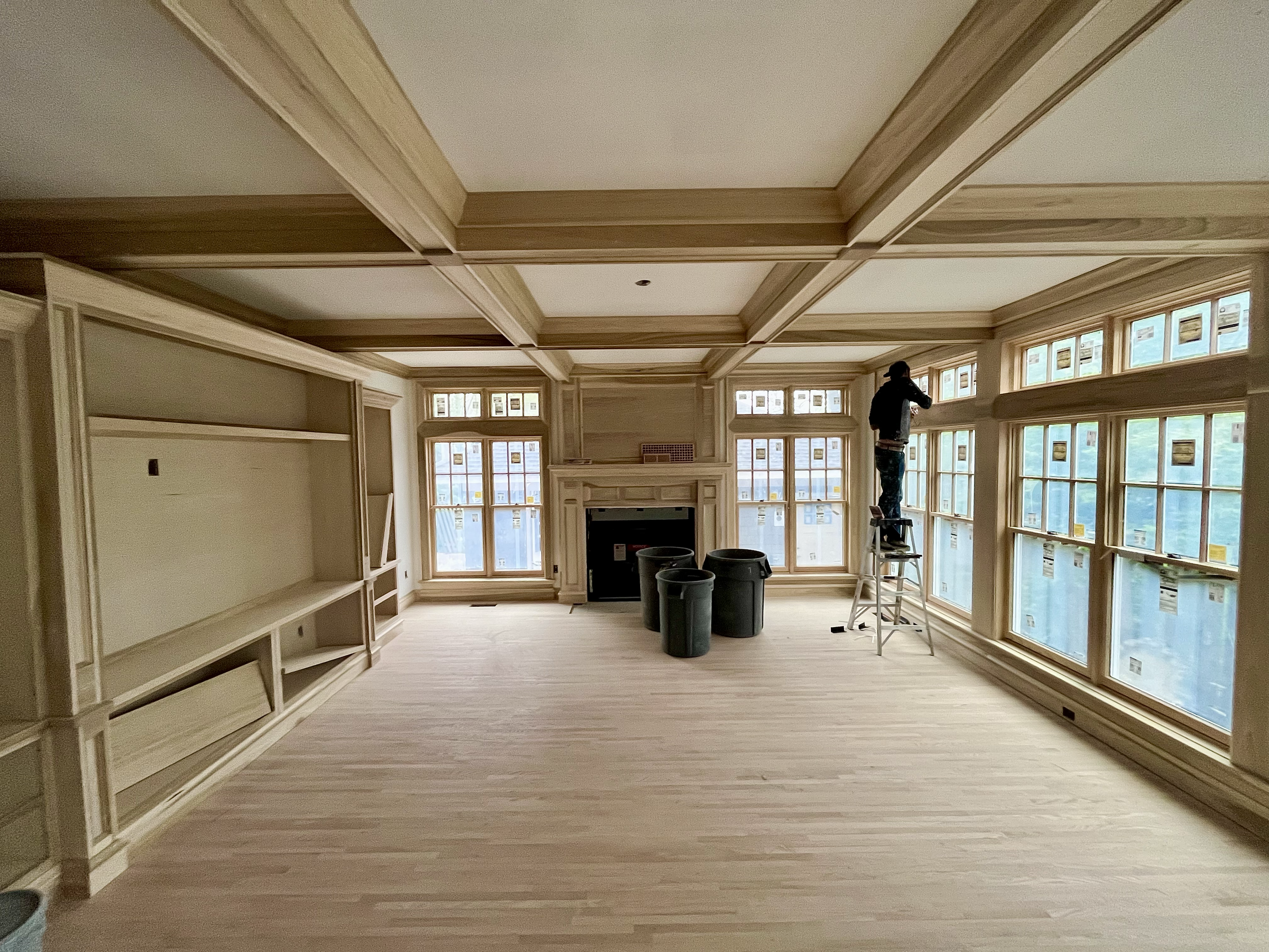 Interior painting and trim work in custom living room with coffered ceiling and painter on ladder in Columbus, Ohio home.
