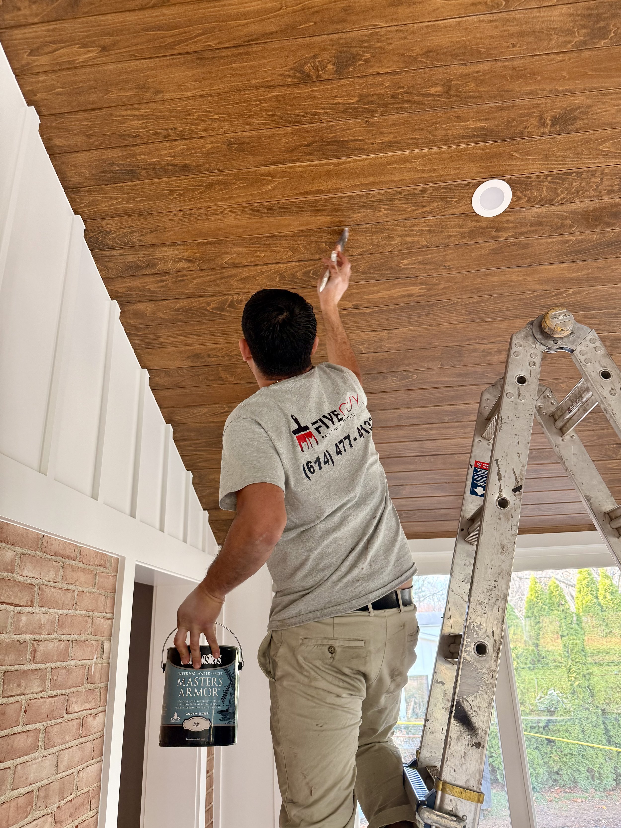 Professional painter staining wood ceiling during interior painting project in Columbus Ohio by Five Guys Painting