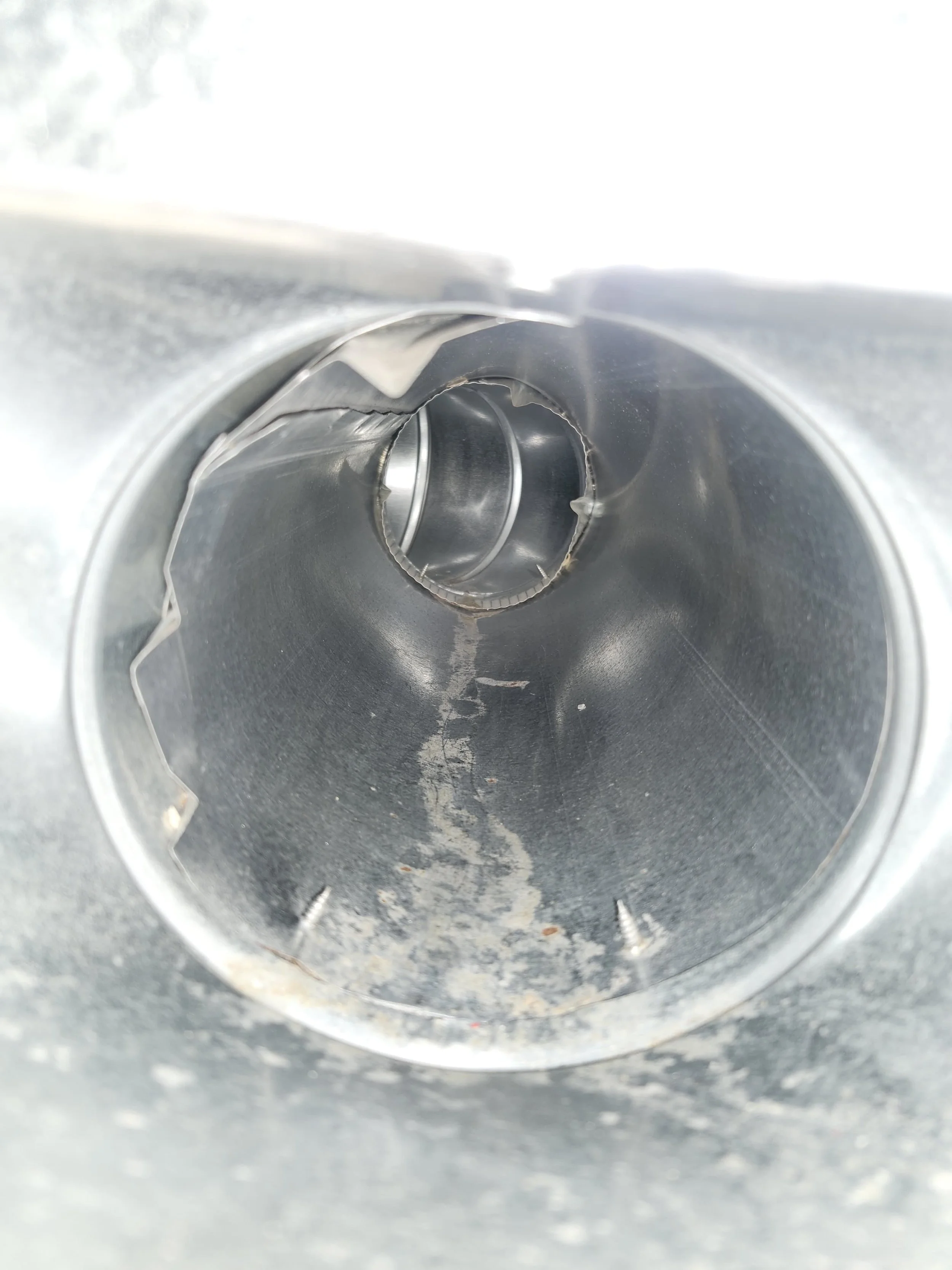 Close-up of the inside of a metallic pipe or tube, showing some scratches and rough edges.