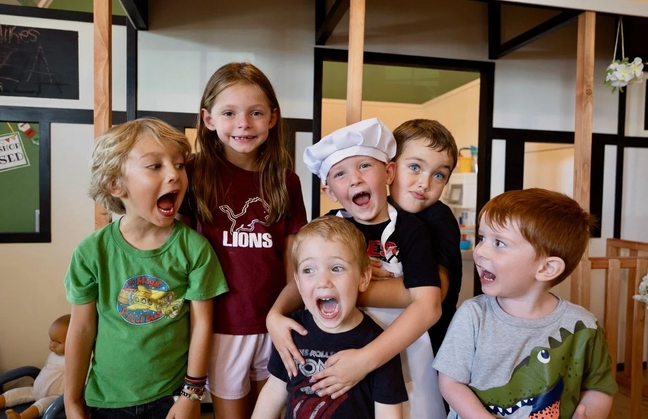 Group of six children, one dressed as a chef, posing playfully in a play area.