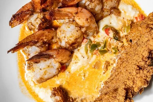 Fried shrimp with a creamy sauce, diced vegetables, and fried chicken on a plate.