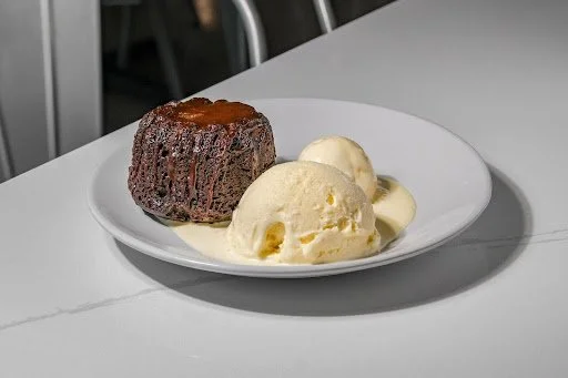 Chocolate lava cake with vanilla ice cream on a white plate.
