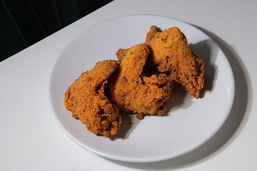 Three pieces of fried chicken on a white plate.