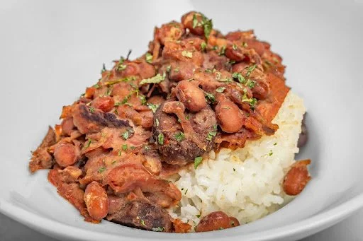 Beef and bean chili served over white rice in a white bowl.