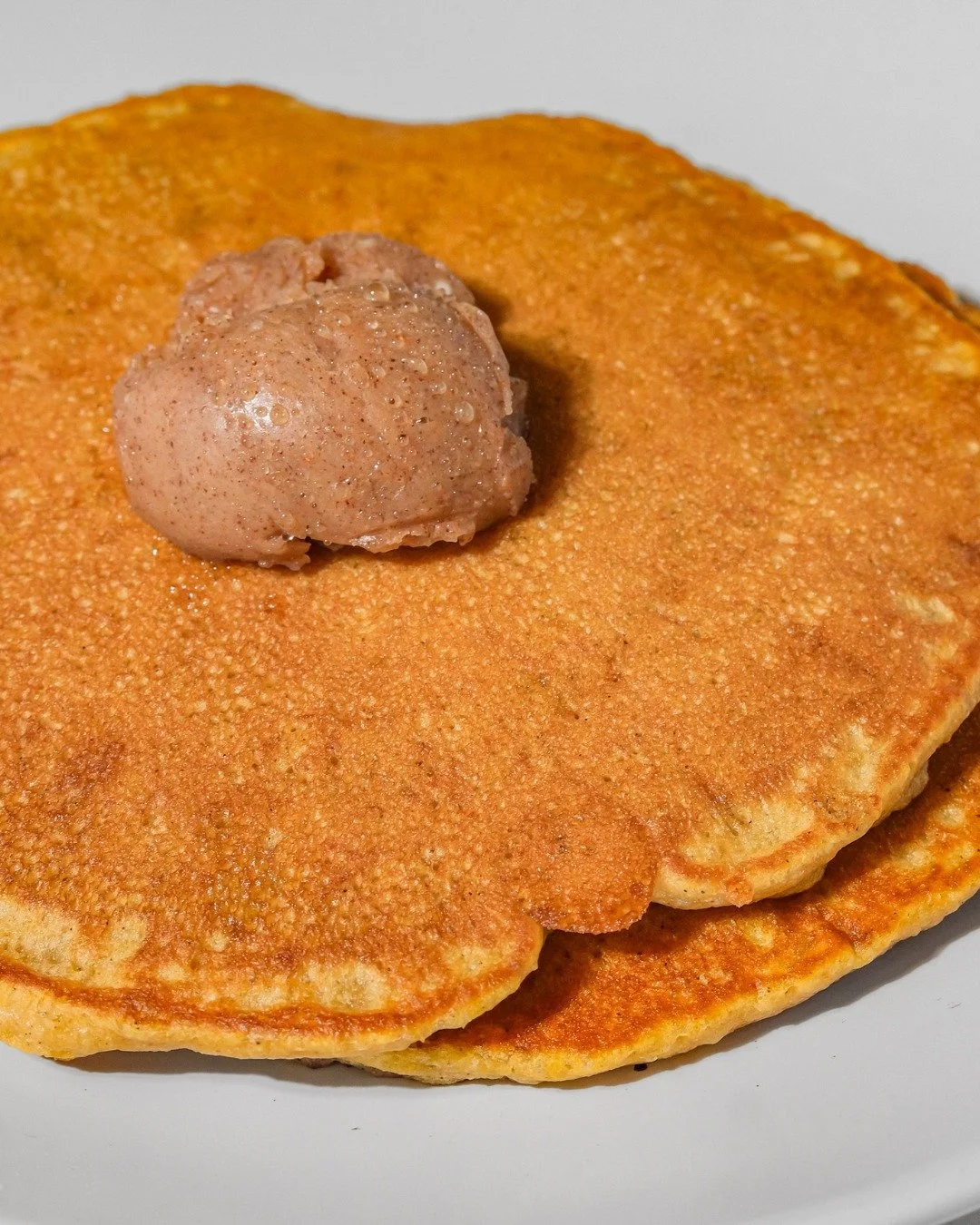Close-up of a pancake with a dollop of pinkish batter or topping on top.