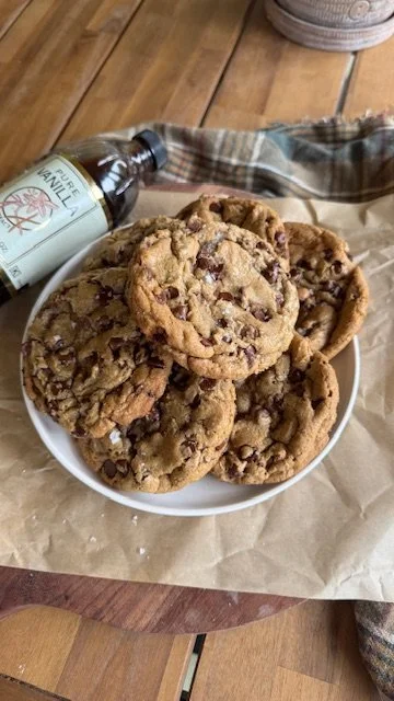plate sitting on a table on parchment paper piled with homemade chocolate chip cookies