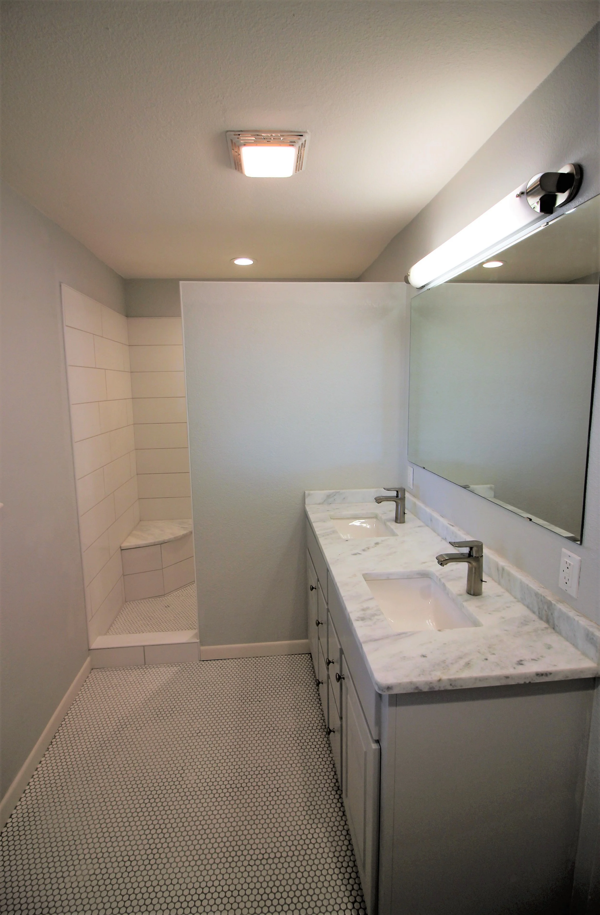 Bathroom with double sink vanity and a walk-in shower in the background.