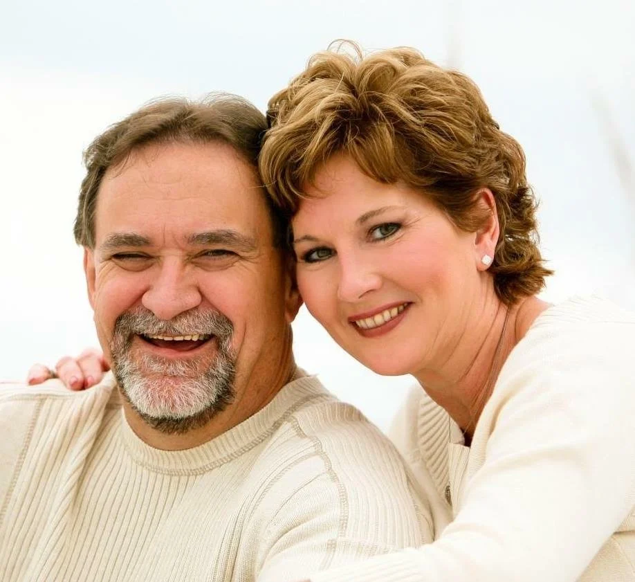 A happy middle-aged man and woman close together, smiling at the camera.