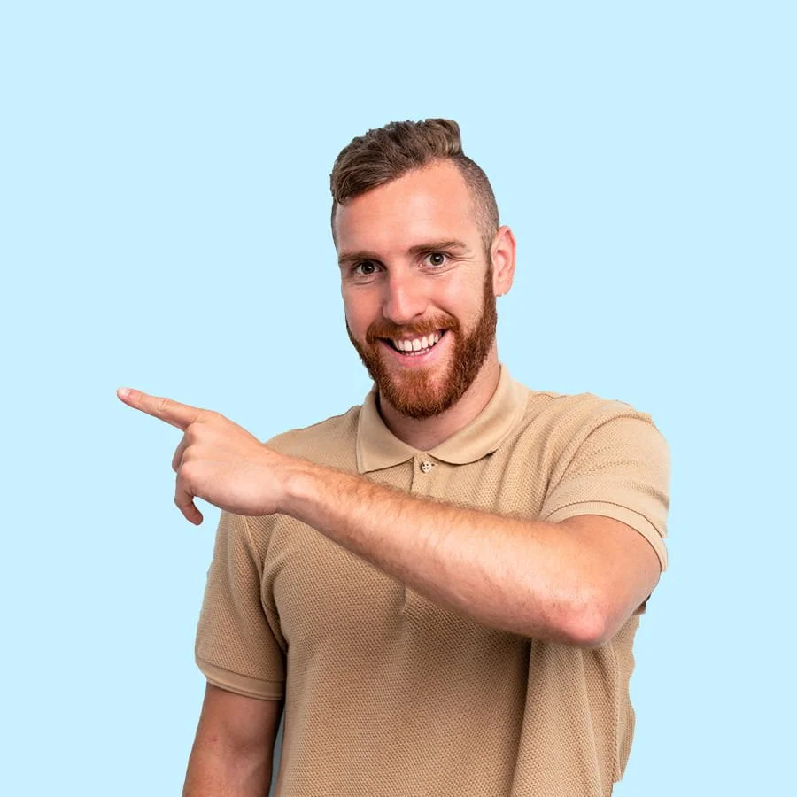 Smiling man with a short beard and brown hair pointing to the left, wearing a beige polo shirt, against a light blue background.