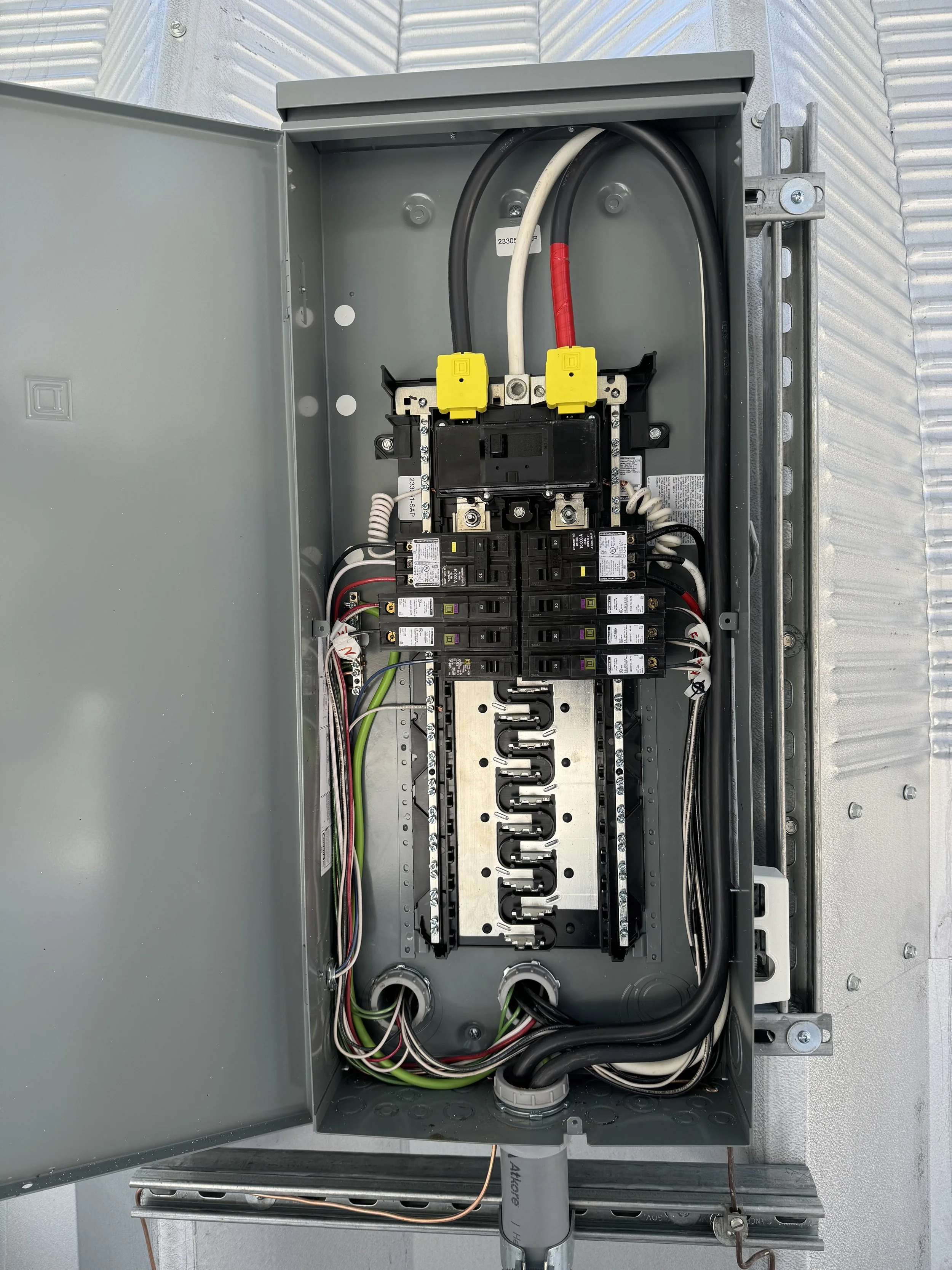 Open electrical panel with circuit breakers, wiring, and connections inside.