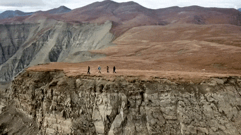 The Great St. Elias Station guests hiking a ridge above layered hills near our McCarthy Alaska lodge.