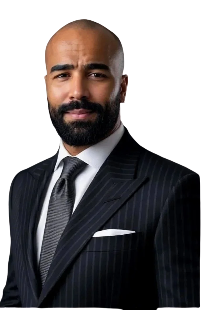 A man with a beard wearing a dark pinstripe suit, white shirt, and gray tie, looking confidently at the camera.