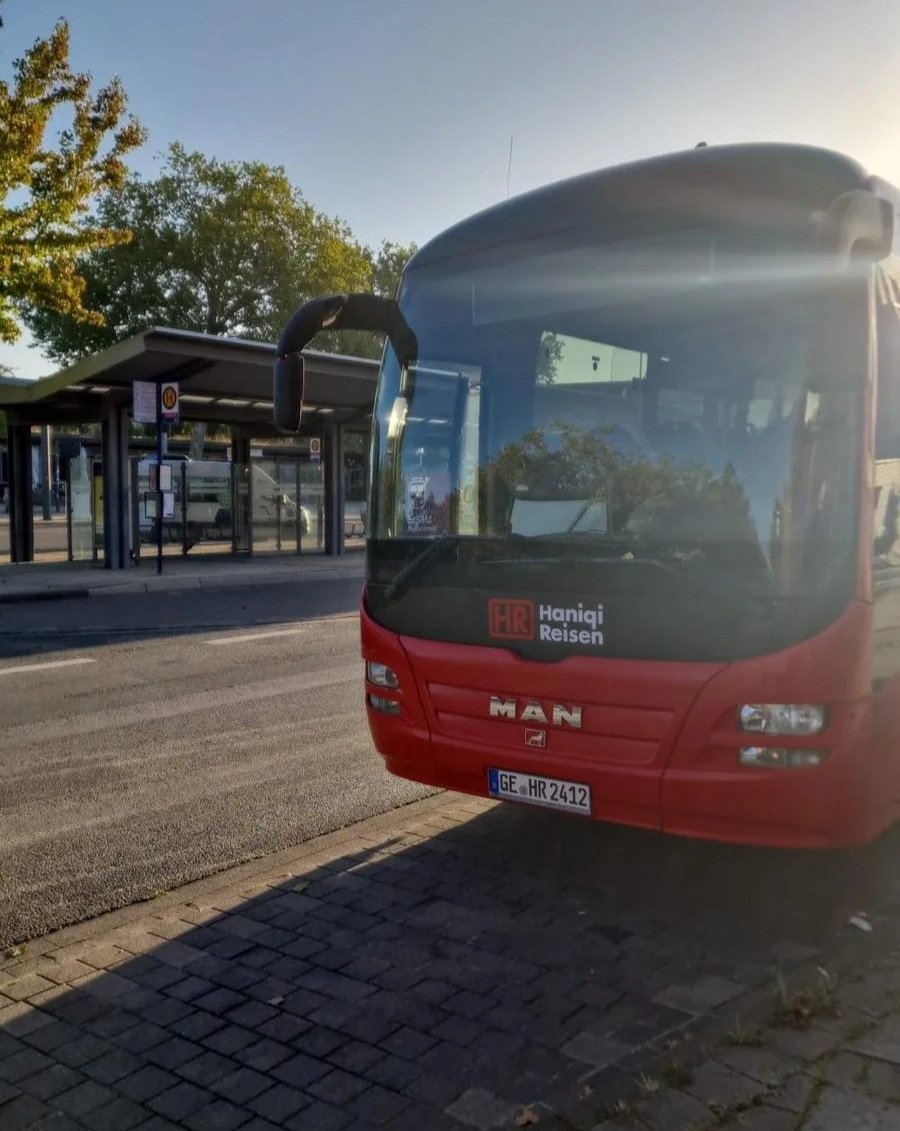 Roter Reisebus von Haniqi Reisen an einer Haltestelle