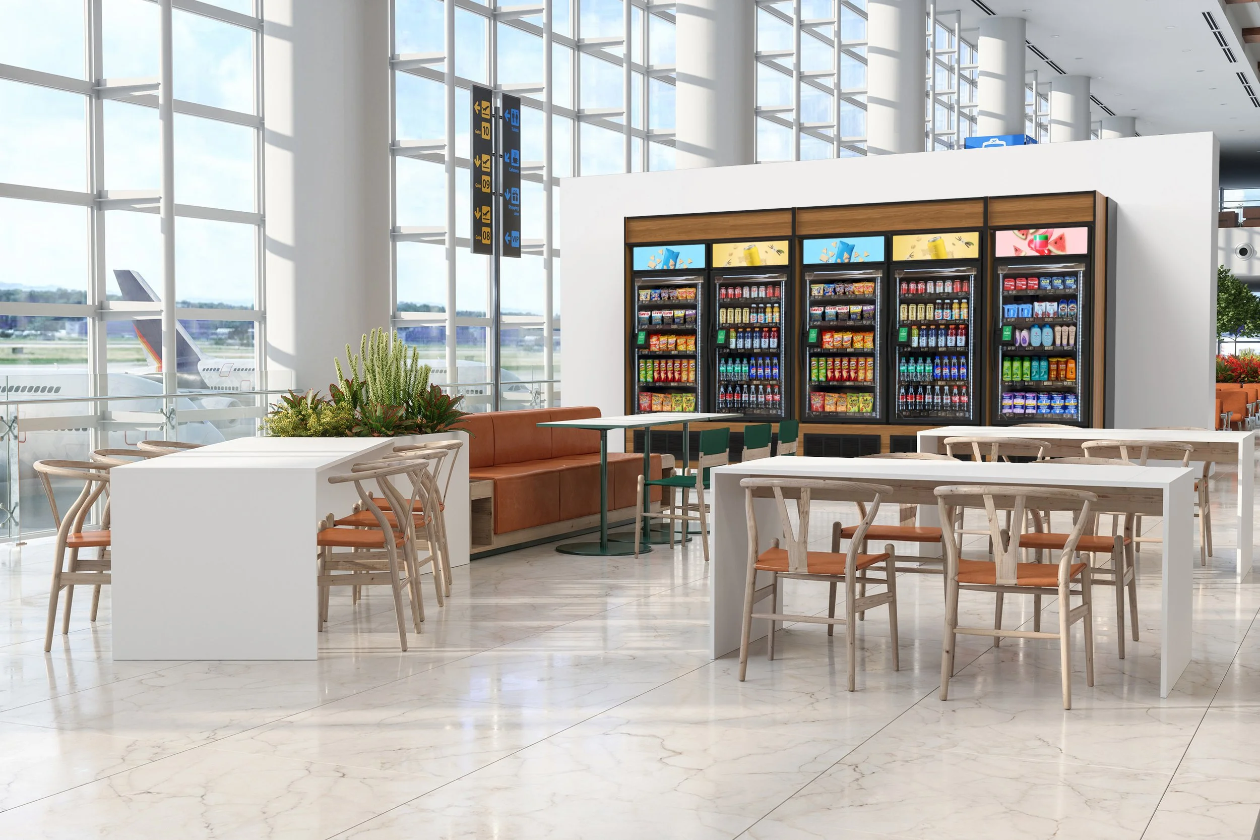 University cafe with round wooden tables, orange chairs, large windows, and two vending machines filled with snacks and beverages.