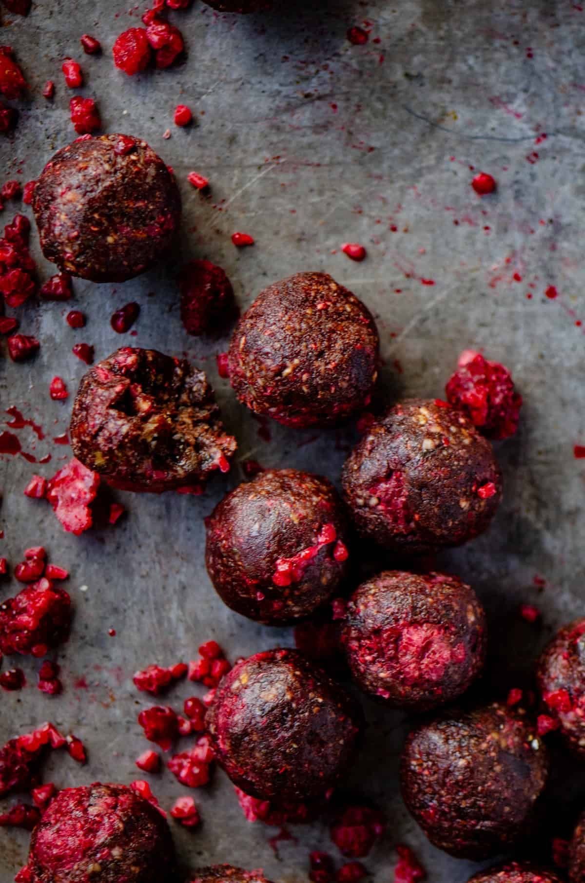 Close-up of raw beetroot balls with some chopped beetroot scattered around on a grey surface.