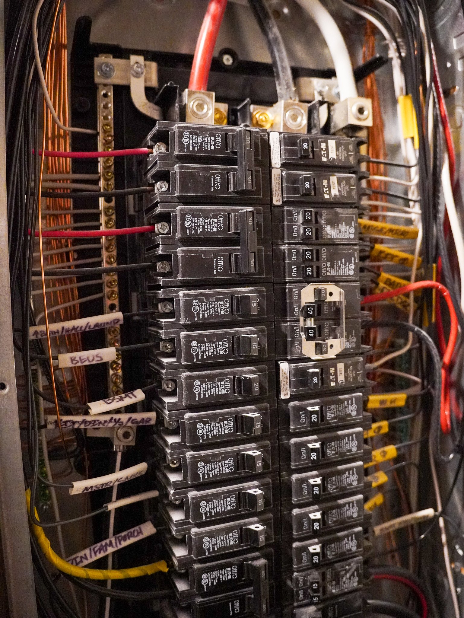 Close-up of an electrical circuit breaker panel with multiple breakers and wiring.