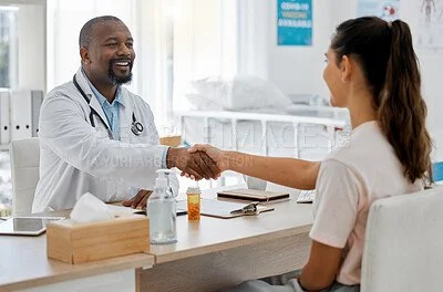 Doctor shaking hands with female patient in a medical office.