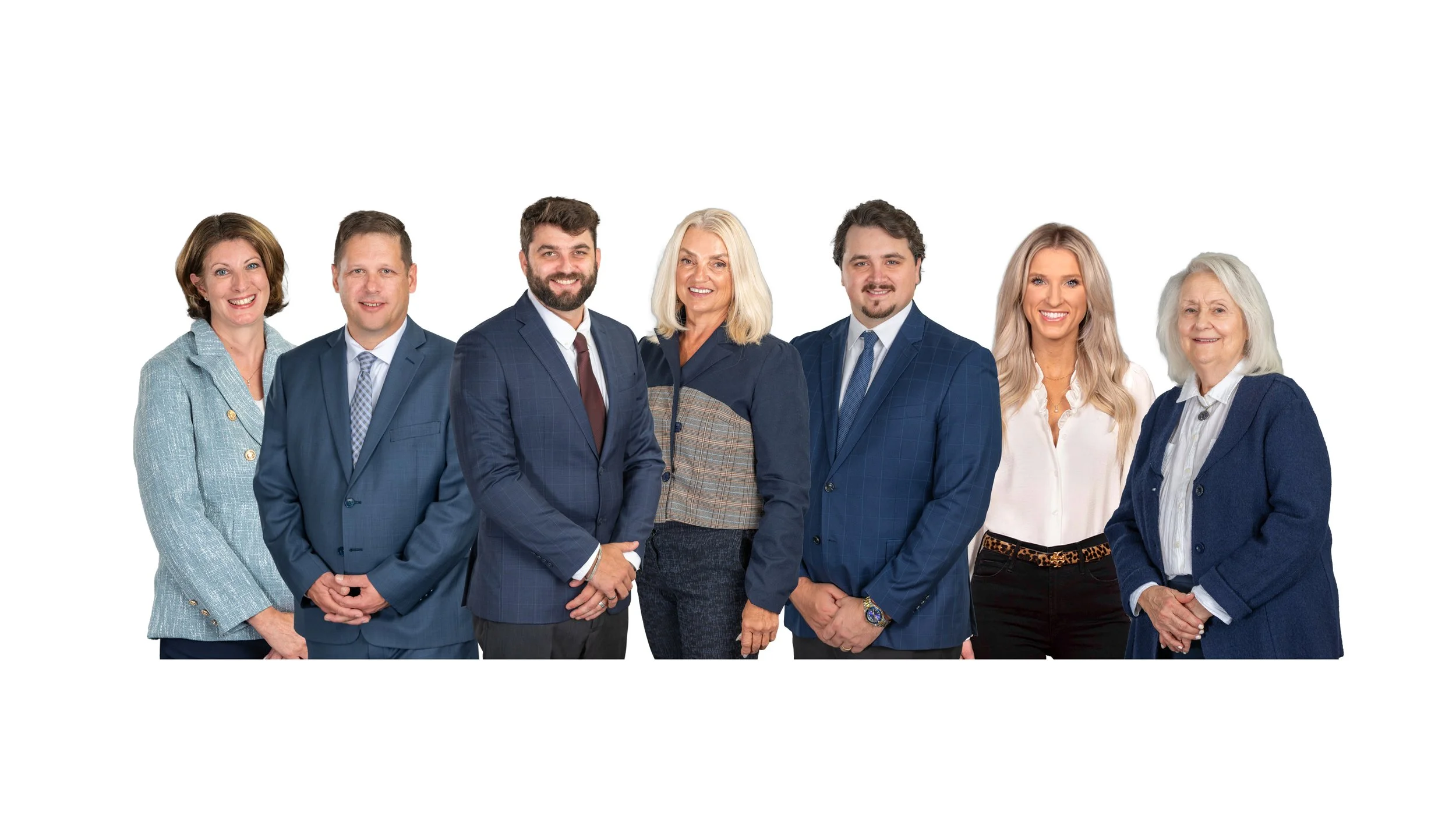 Group of seven professionally dressed adults posing together against a white background.