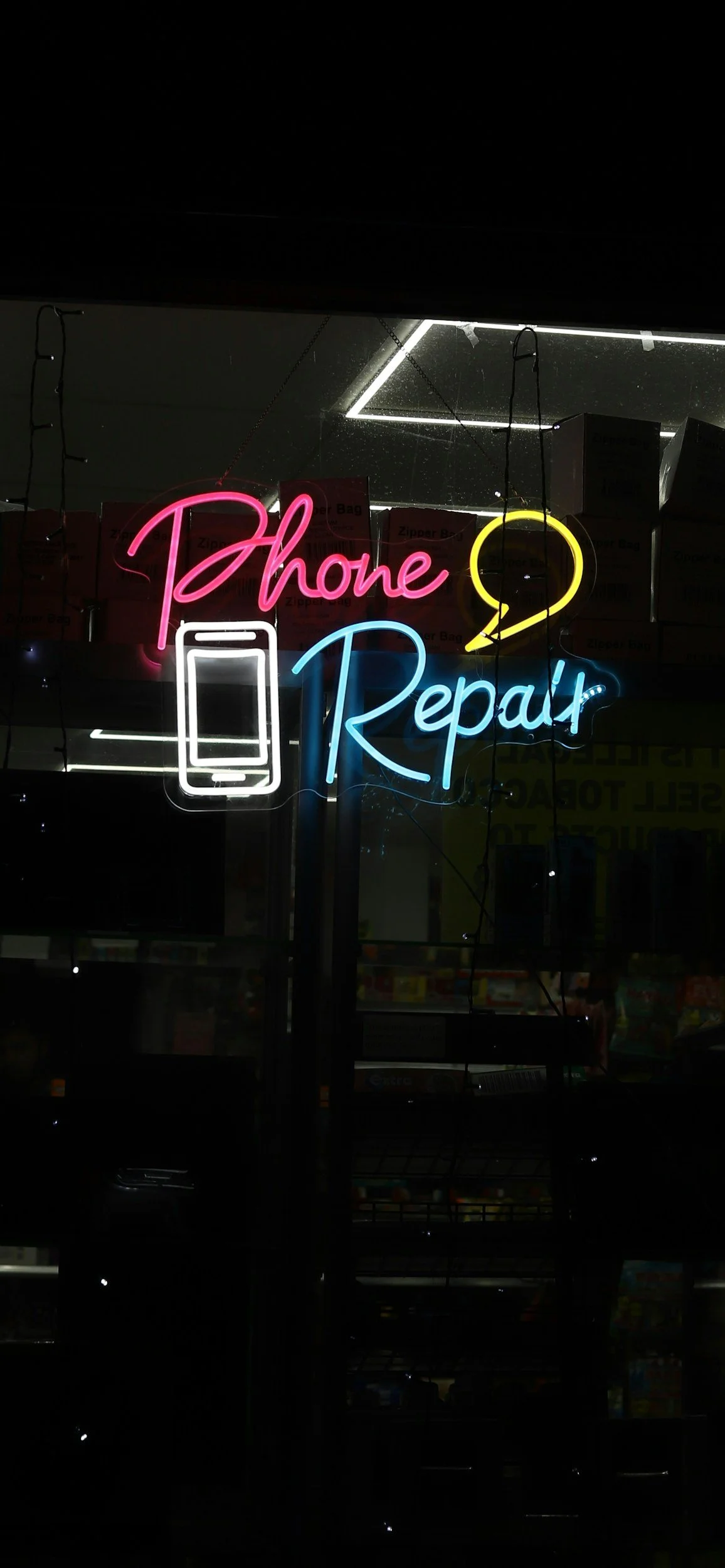 Neon sign reading 'Phone Repair' with an icon of a smartphone and speech bubble