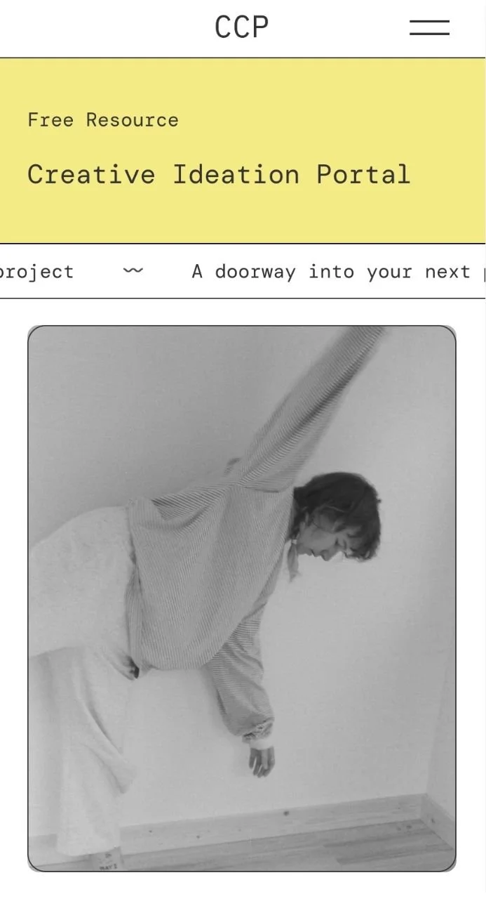 A woman in a striped long-sleeve shirt and white skirt is balancing on her right foot with her left arm raised, leaning against a plain wall in a minimalist room with a wooden floor.