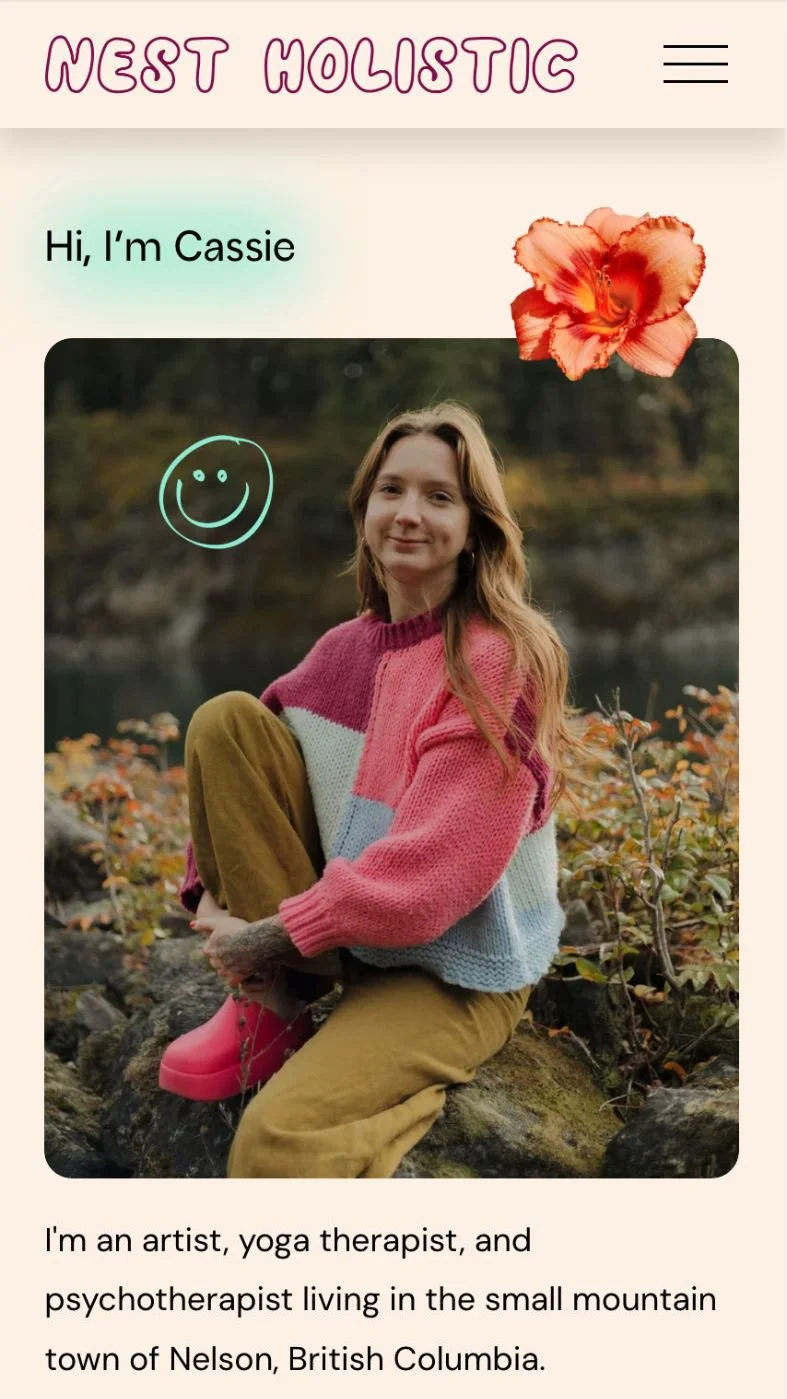 Portrait of a woman sitting outdoors on rocks near water, wearing a colorful knitted sweater, with a blurred natural background, and a flower overlay in the top right corner, on a website titled "Nest Holistic".