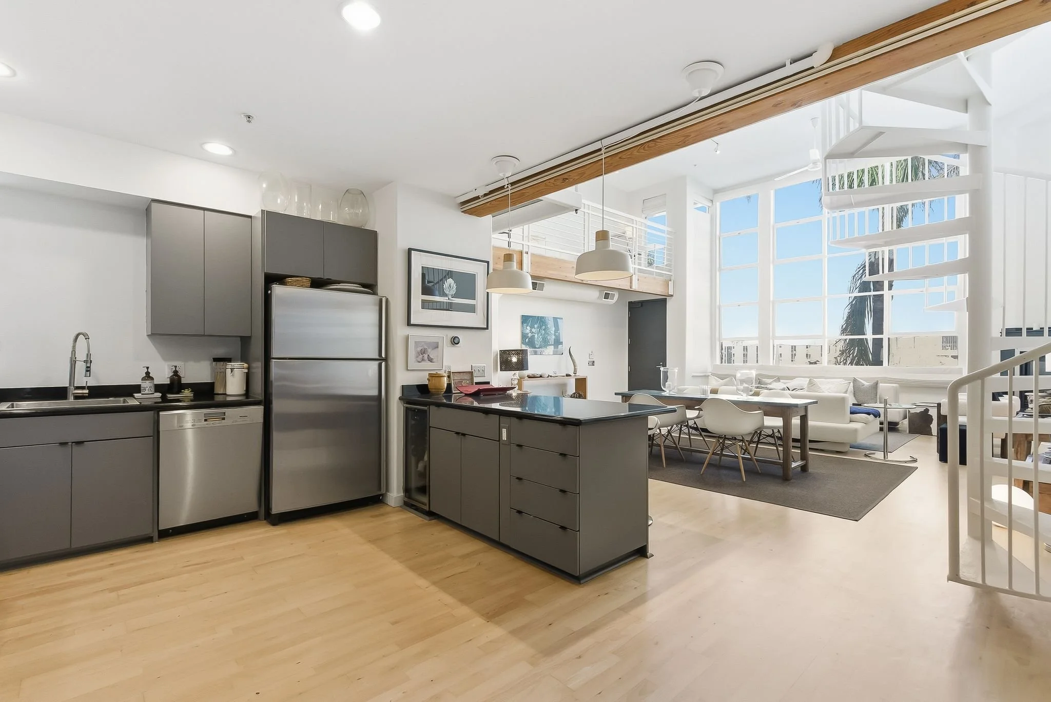Open-concept modern apartment with kitchen and living room, large windows, neutral tones, and minimalist decor.