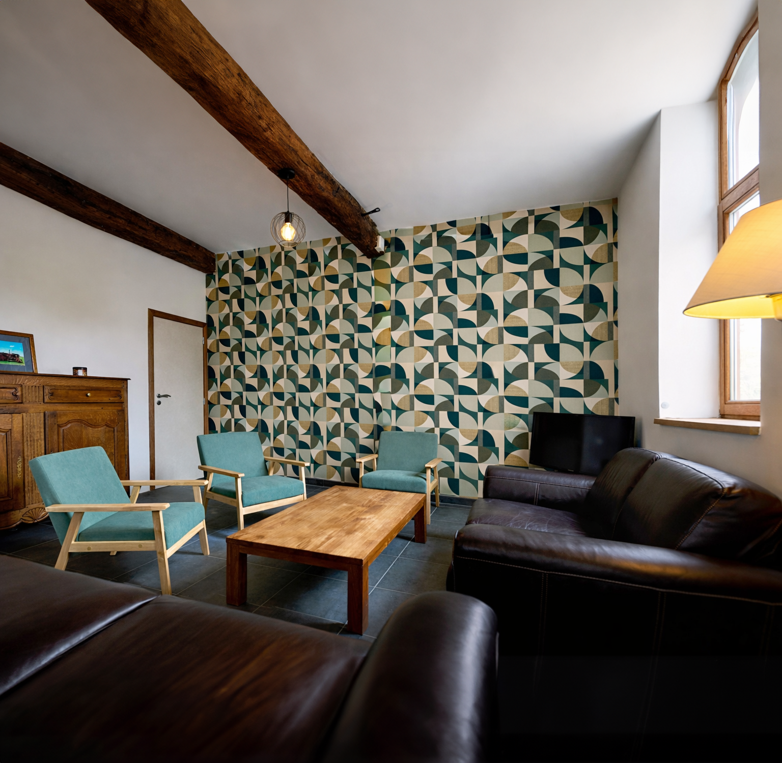 Salon avec canapé en cuir, fauteuils en tissu turquoise, table en bois du gîte « Les Campanes » à Vellereille-le-Sec (Estinnes, Belgique) est une fermette du XVIIIe siècle rénovée, offrant un séjour haut de gamme pour 8 personnes